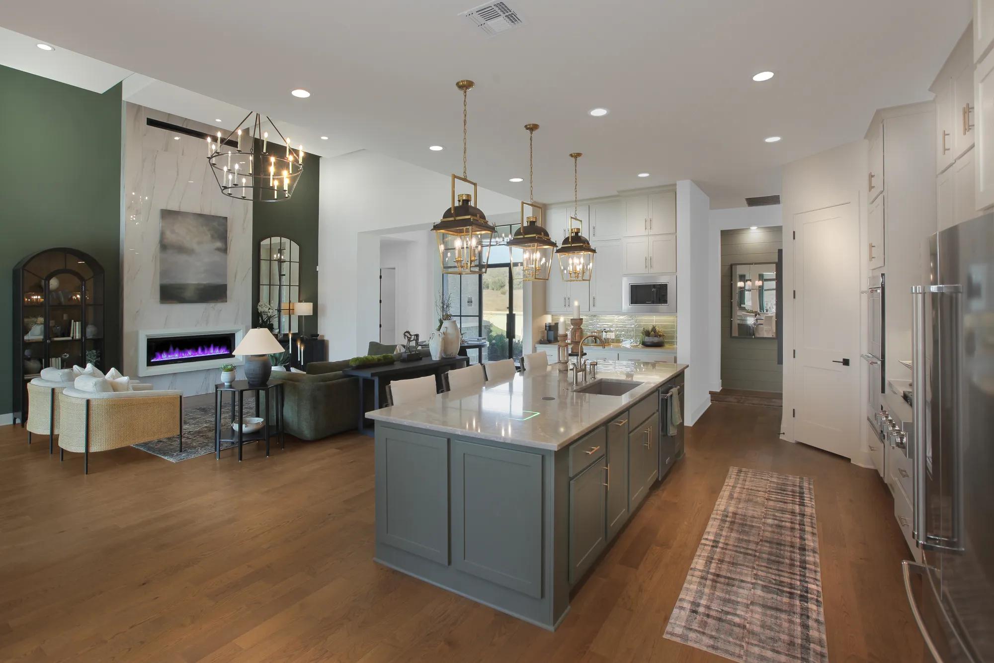 Spacious kitchen with oversized island, mixed cabinetry tones, and designer lighting in a custom Drees home