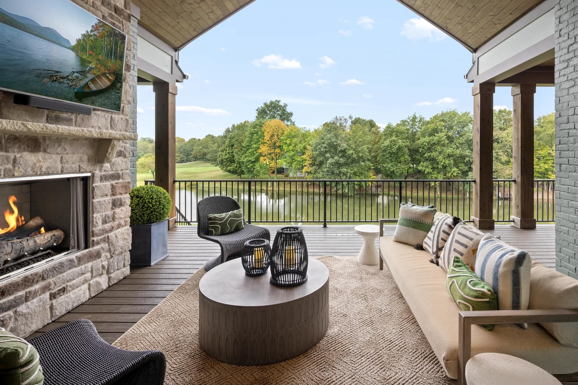 Custom home outdoor living area with fireplace and vaulted ceiling overlooking the water