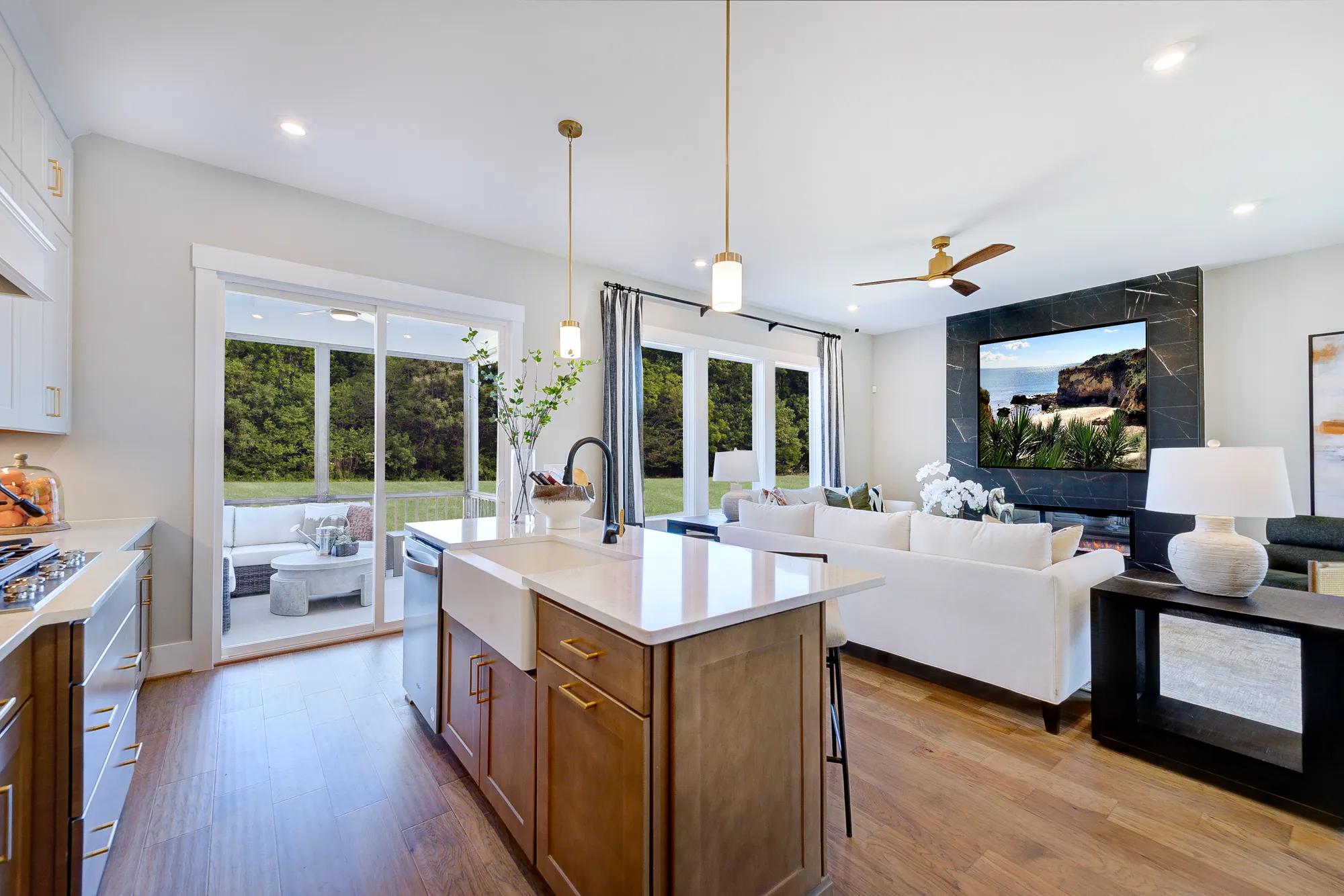 brown island with white counter top and sink, large windows in the distance bringing in light into the family room