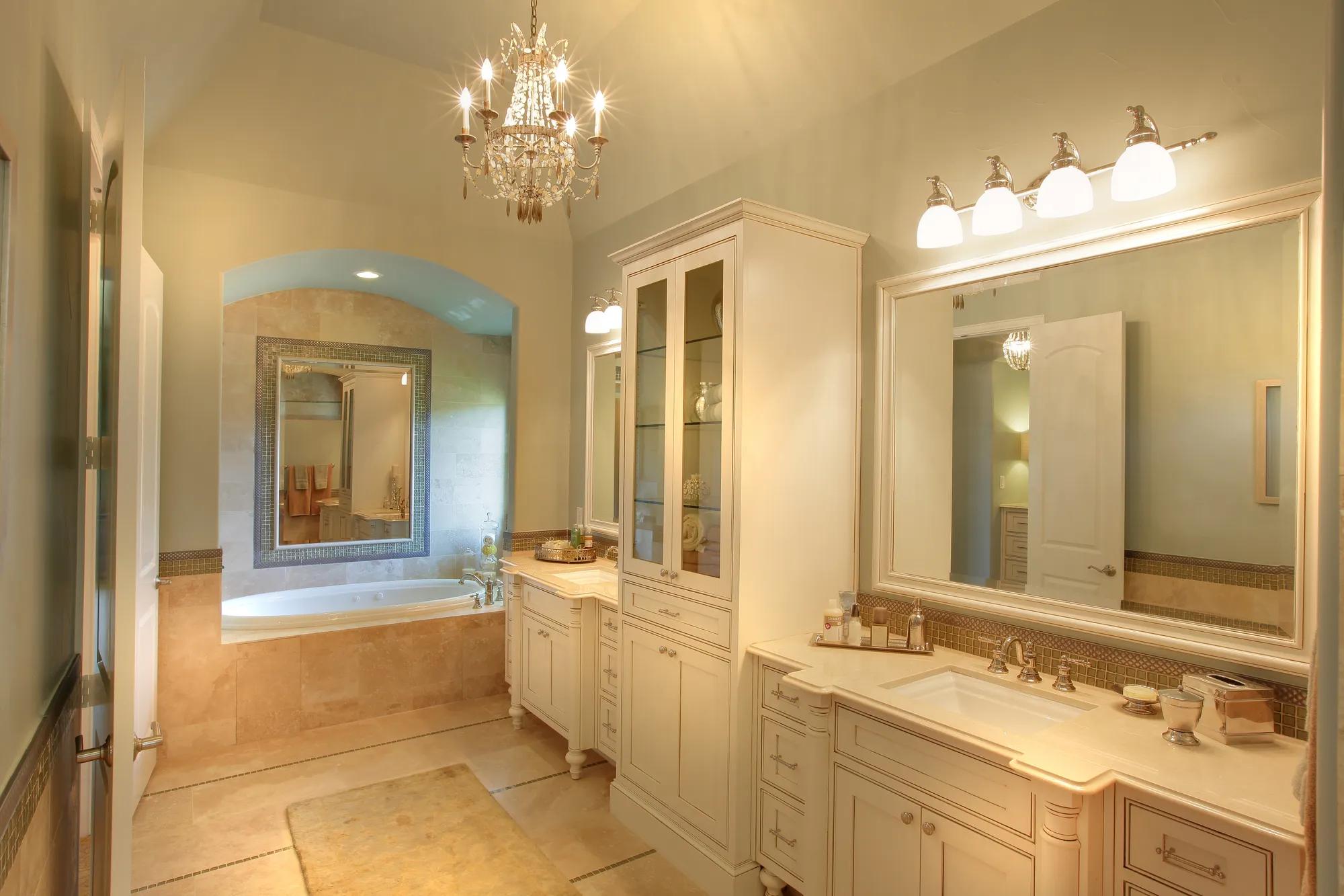 Primary Bath with chandelier, soak tub, ceramic tile and double vanities