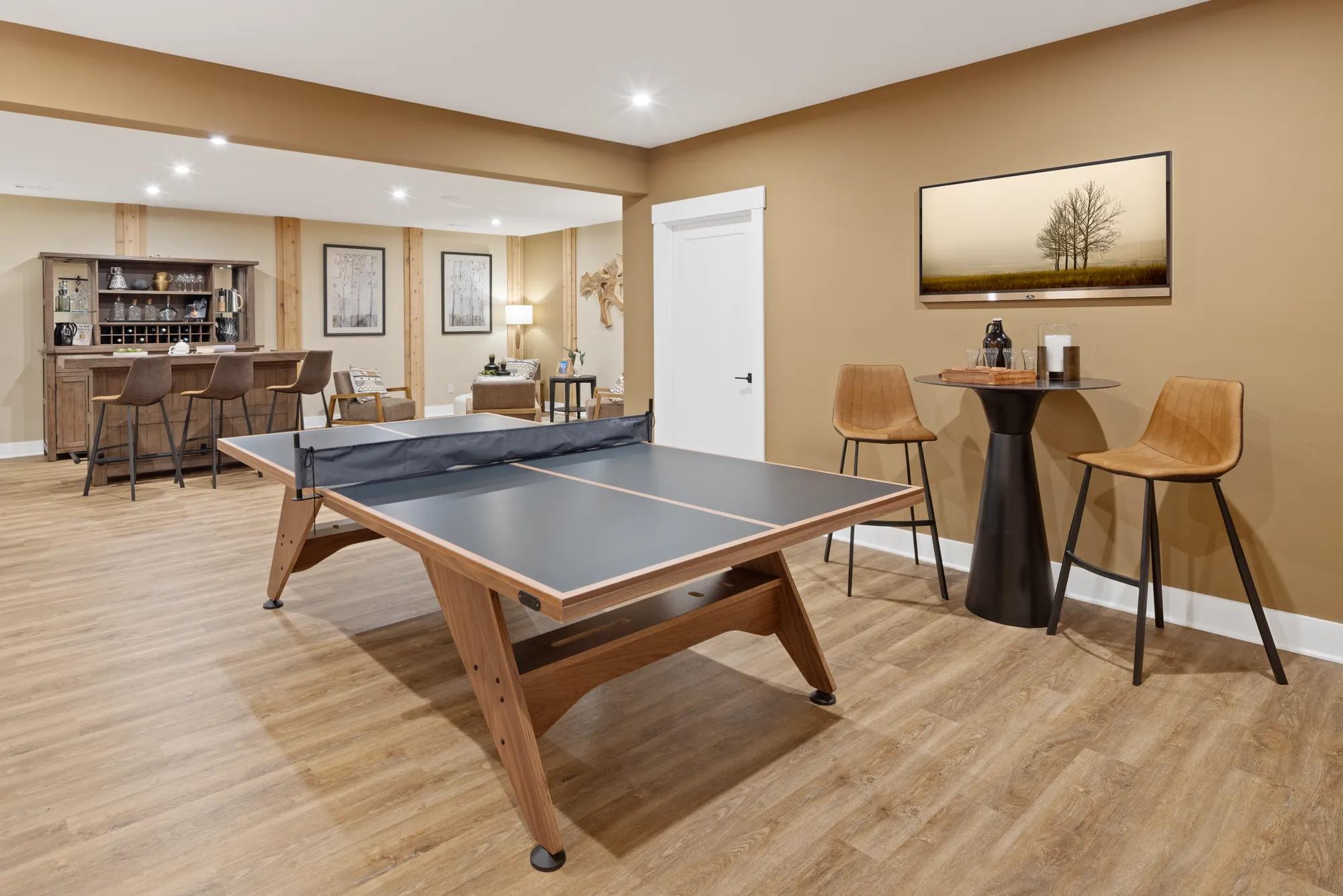 Custom home finished basement with hardwood floors, bar, and table tennis