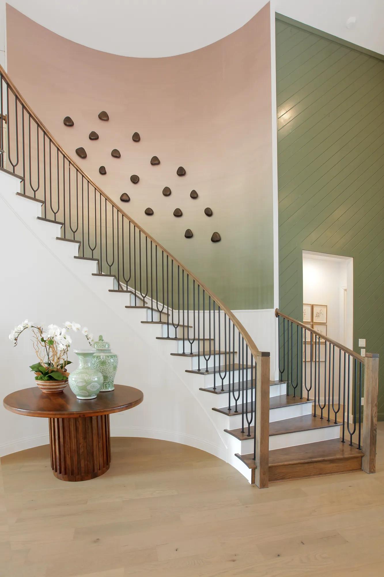 Custom home curved staircase with hardwood steps and green and pink accent wall