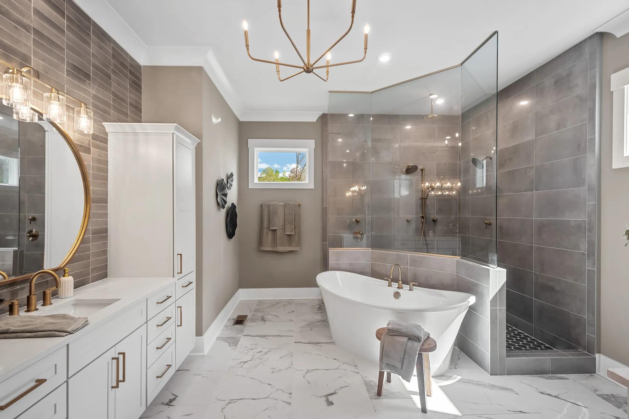 Custom home primary bathroom with tile and glass walk through shower and freestanding tub