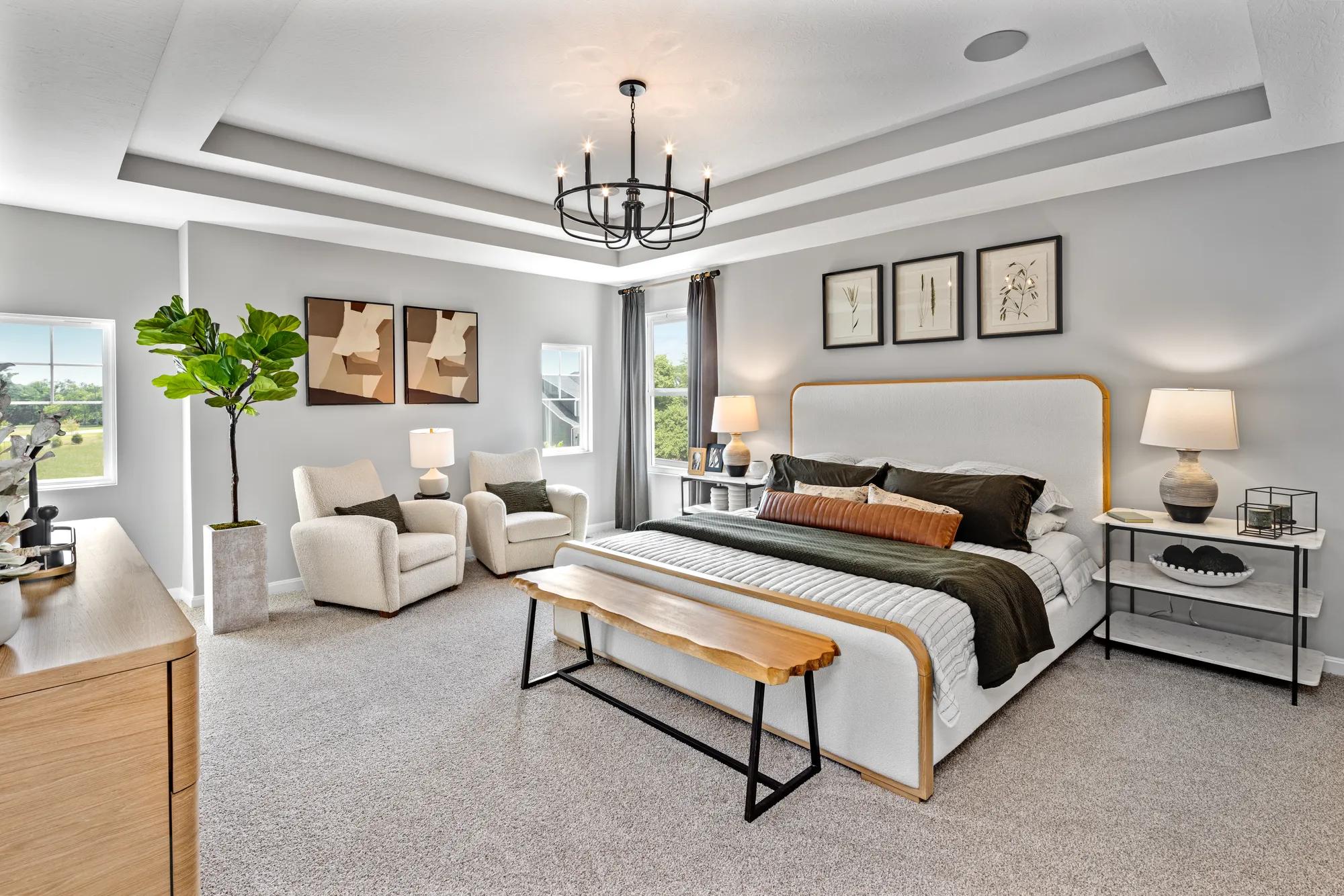primary bedroom with tray ceiling and chandelier