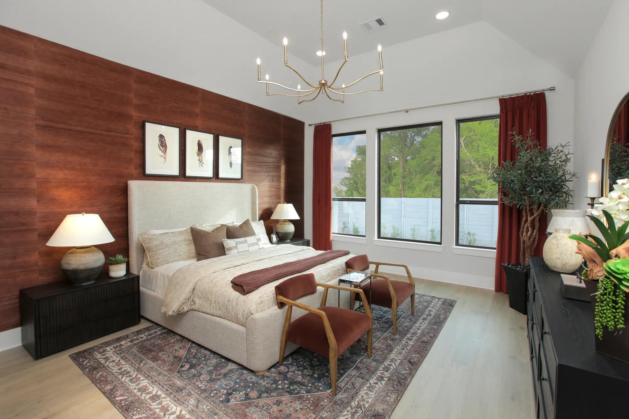 Custom home primary suite bedroom with muted red wallpaper accent wall
