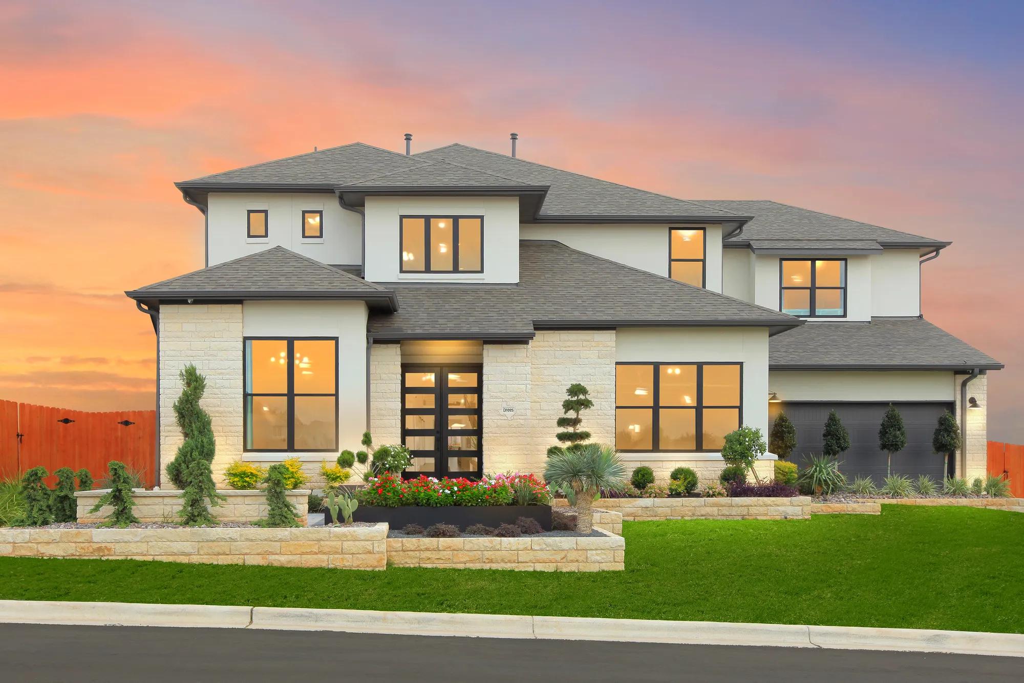 Custom home exterior and landscaped front yard at sunset