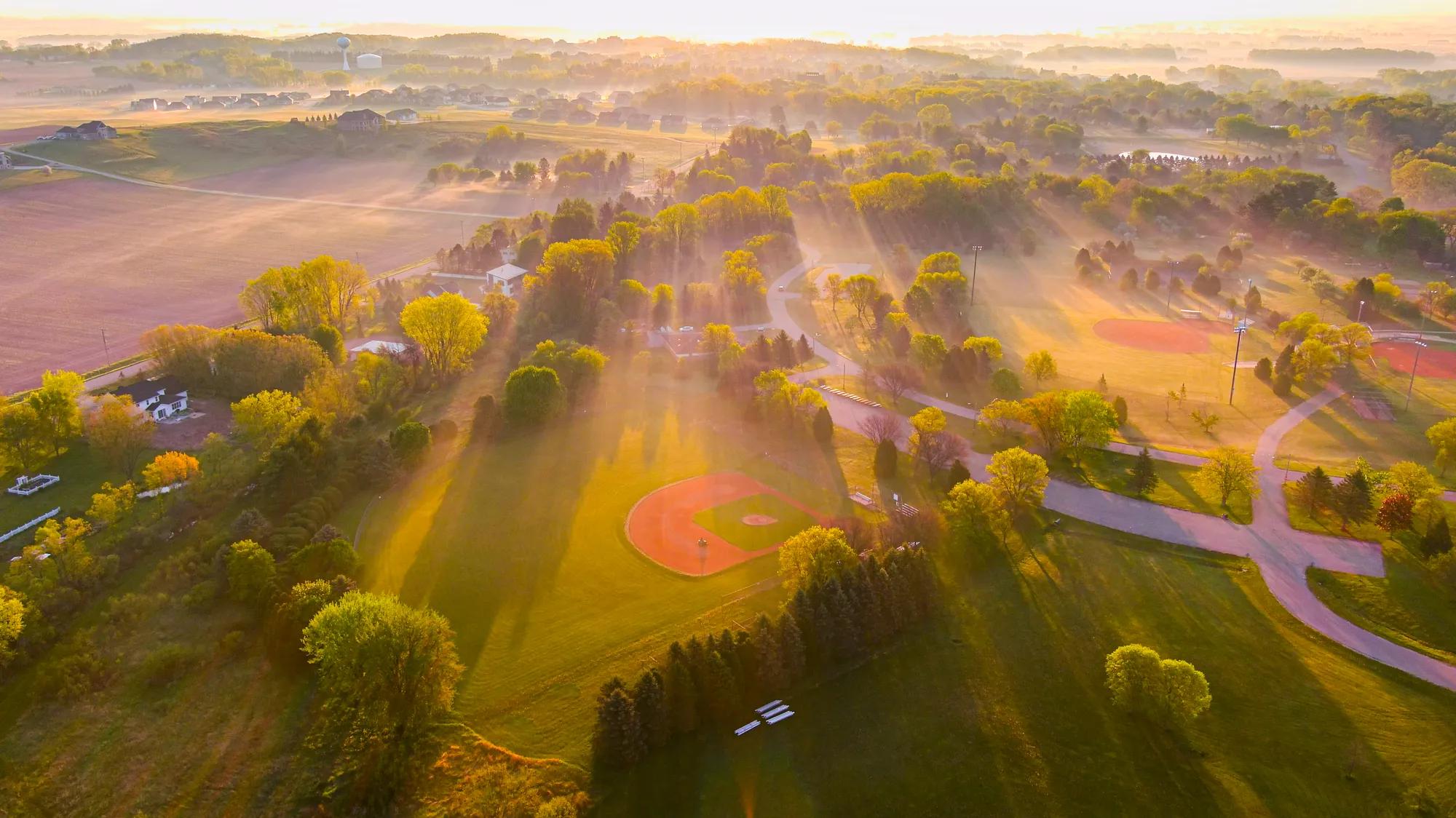 Aerial view of ball park at sunrise with long shadows in misty air.