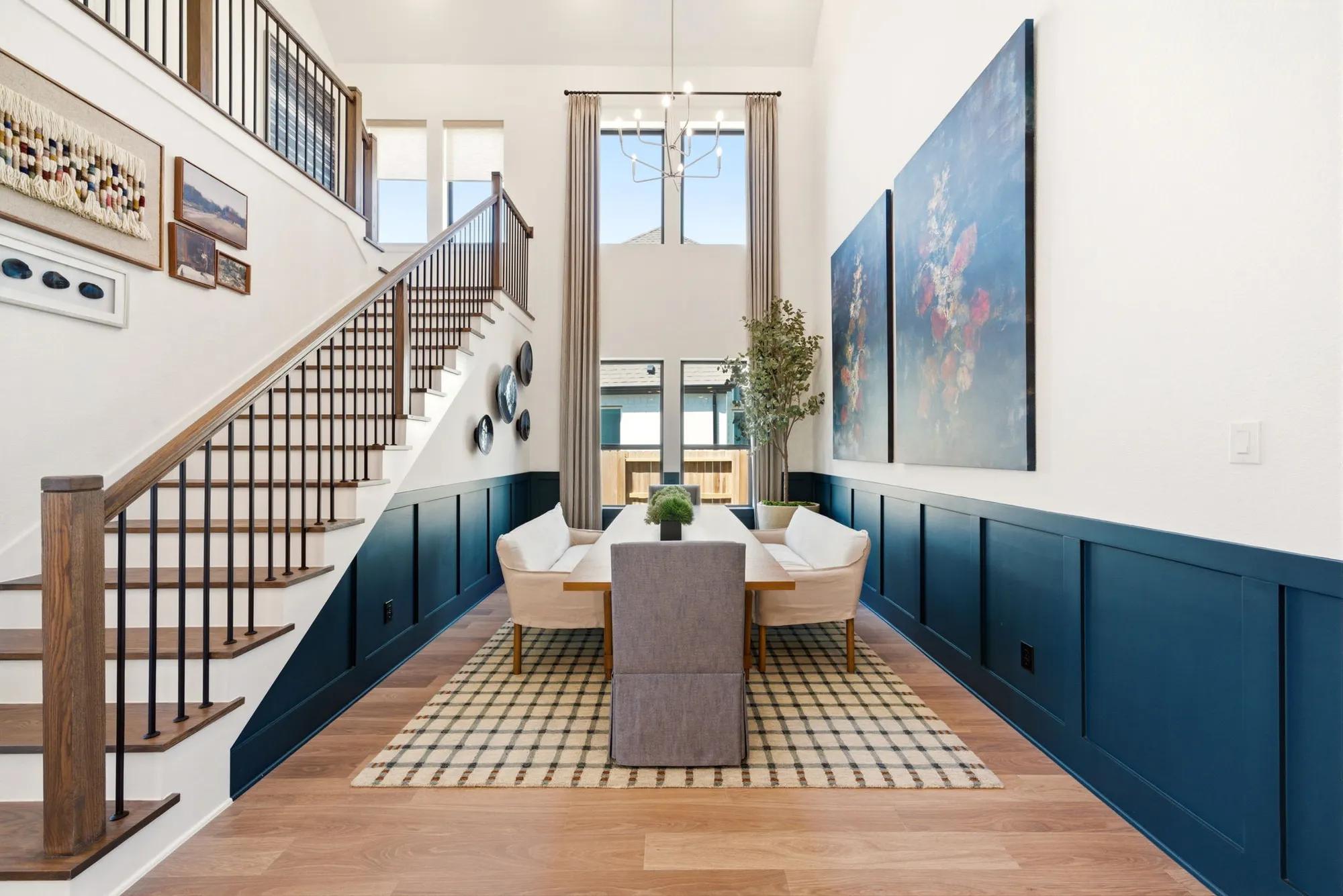 Texas custom home two-story dining room with blue wainscoting walls and open hardwood step staircase