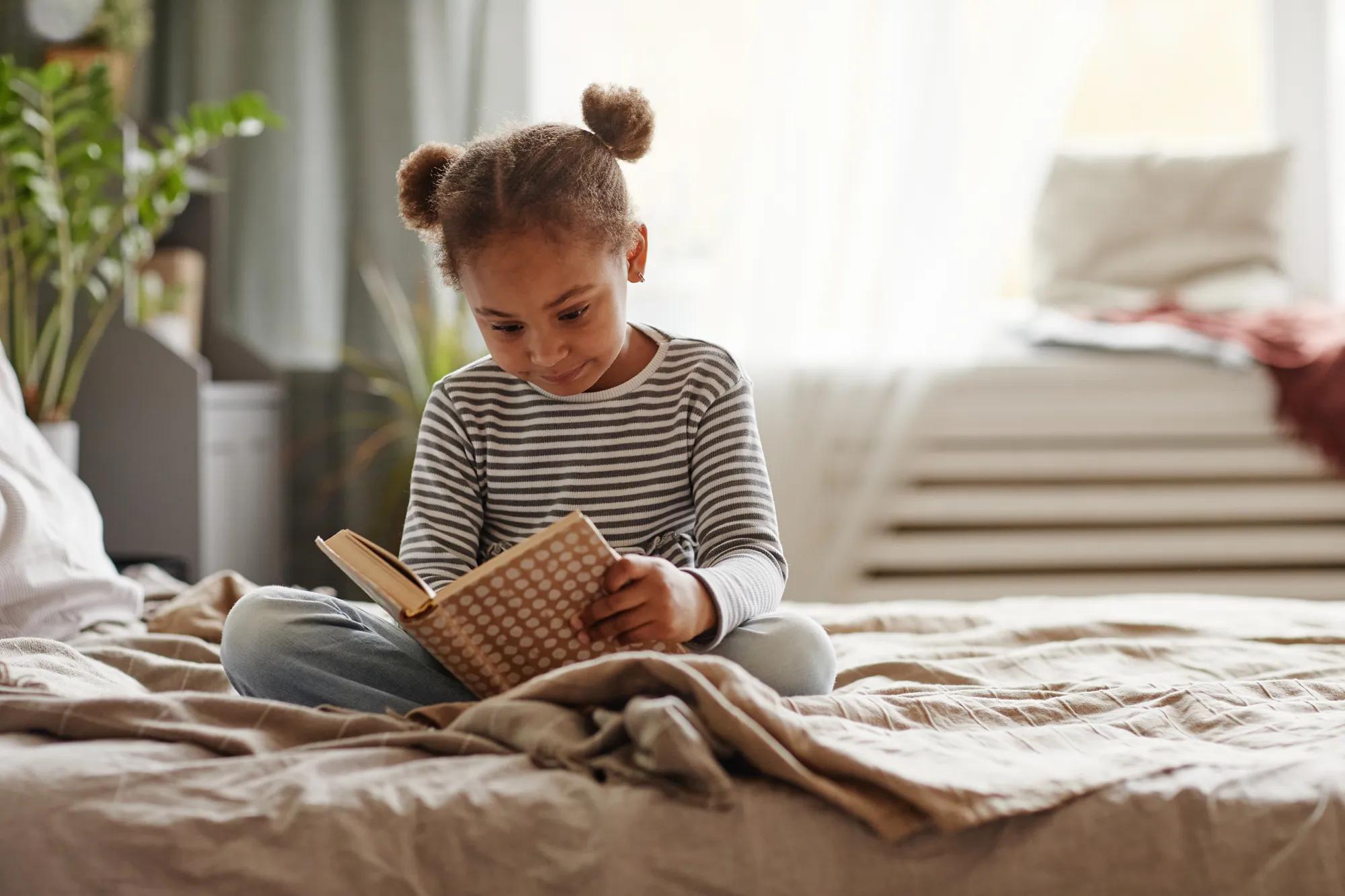 Girl reading book in bedroom