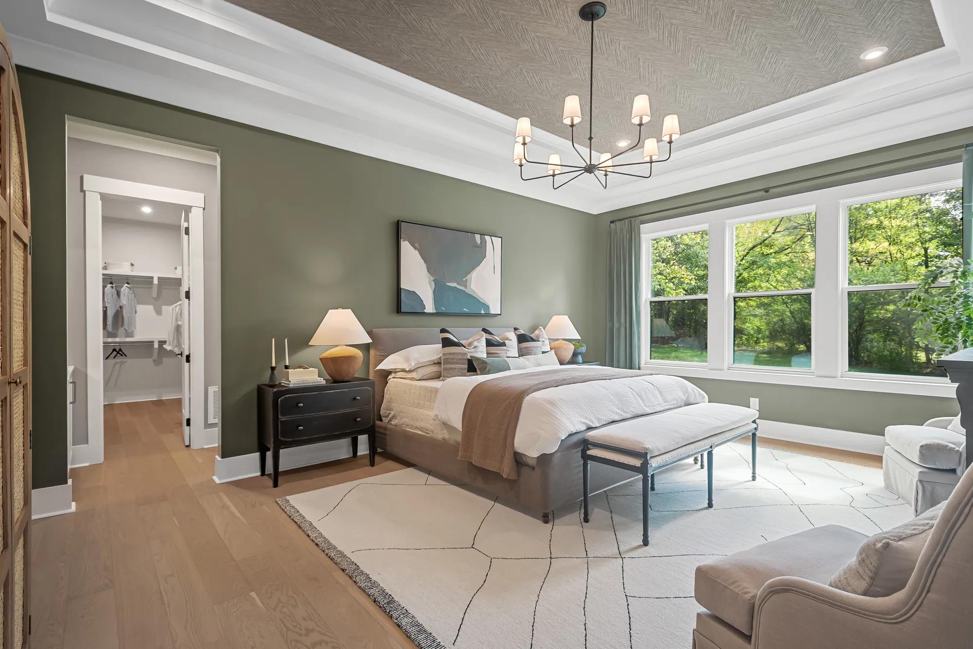 New home primary suite bedroom with ceiling accent and green walls