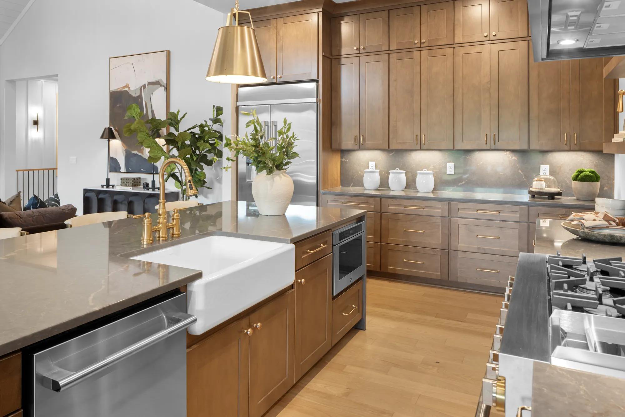 New home kitchen with wood cabinets, farm sink in island, and stainless steel appliances