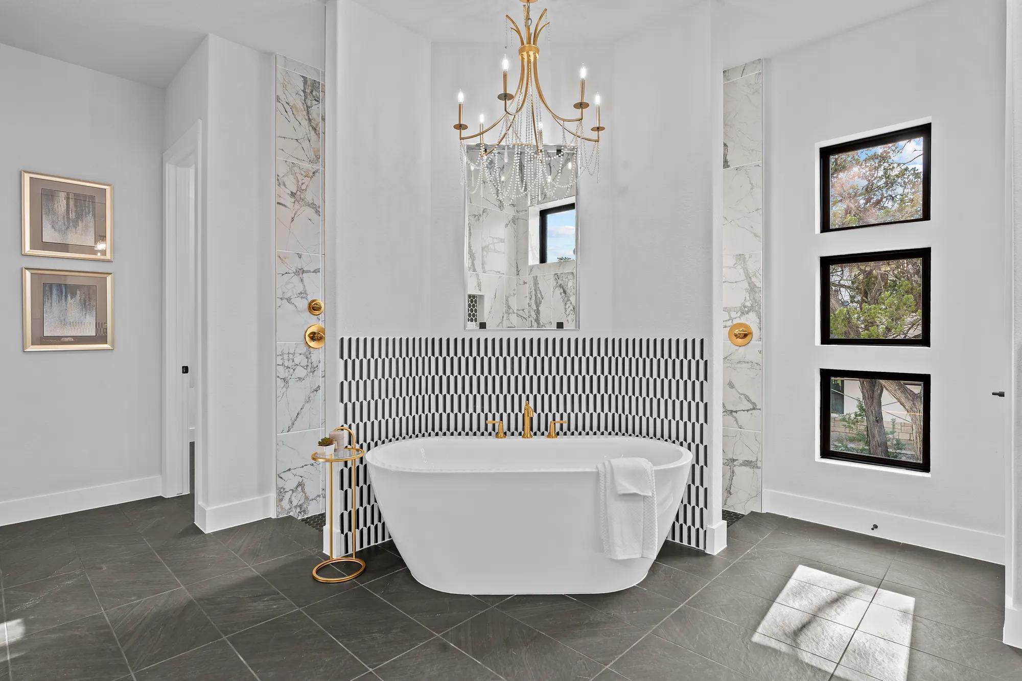 Custom home primary suite bathroom with double shower walkthrough and freestanding tub with gold finishes 