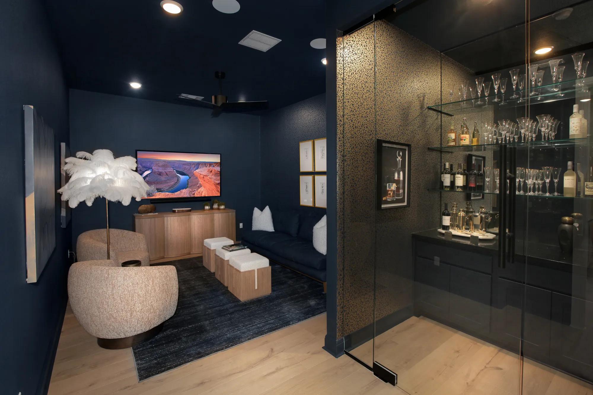 Custom home wine room with glass shelves, glass walls, and black counters, inside media room