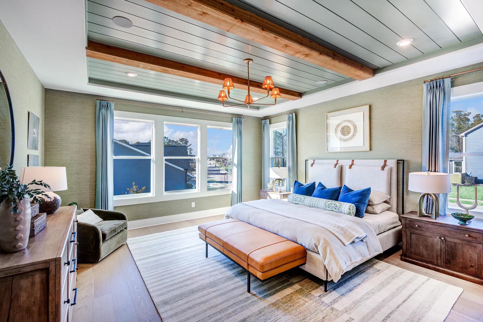 Custom home primary bedroom with paneling on ceiling and wood beam accents