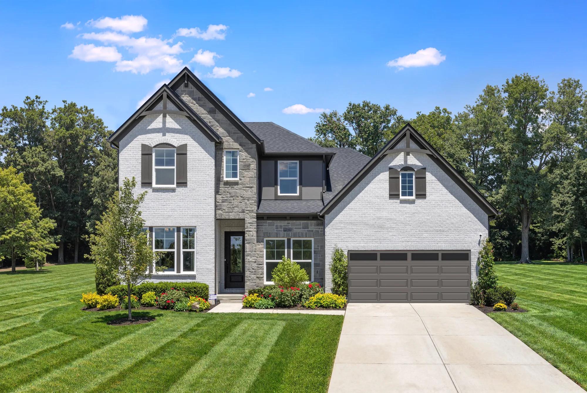Two-story custom home with white brick and gray stone exterior with brown shutters and front entry garage door