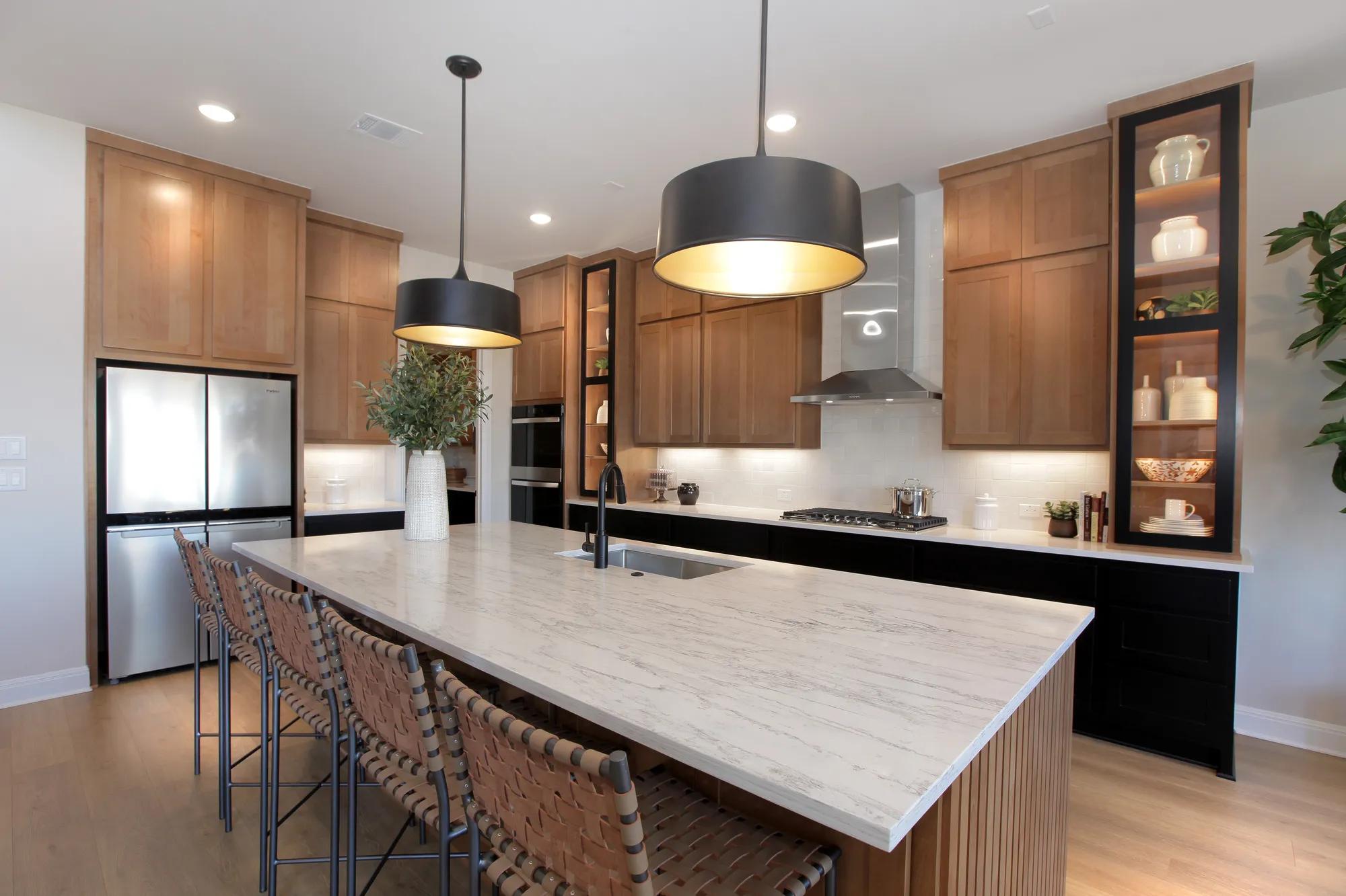 Custom home kitchen with statement glass front cabinets, black lower cabinets, and light wood upper cabinets