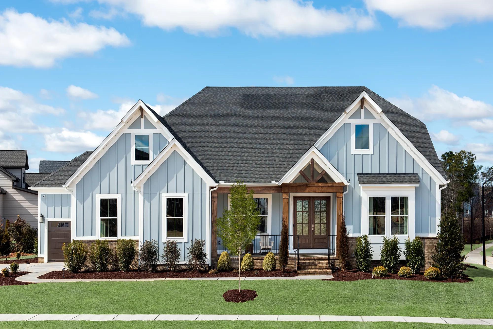 Blue board and batten siding home with dark cedar front door and columns