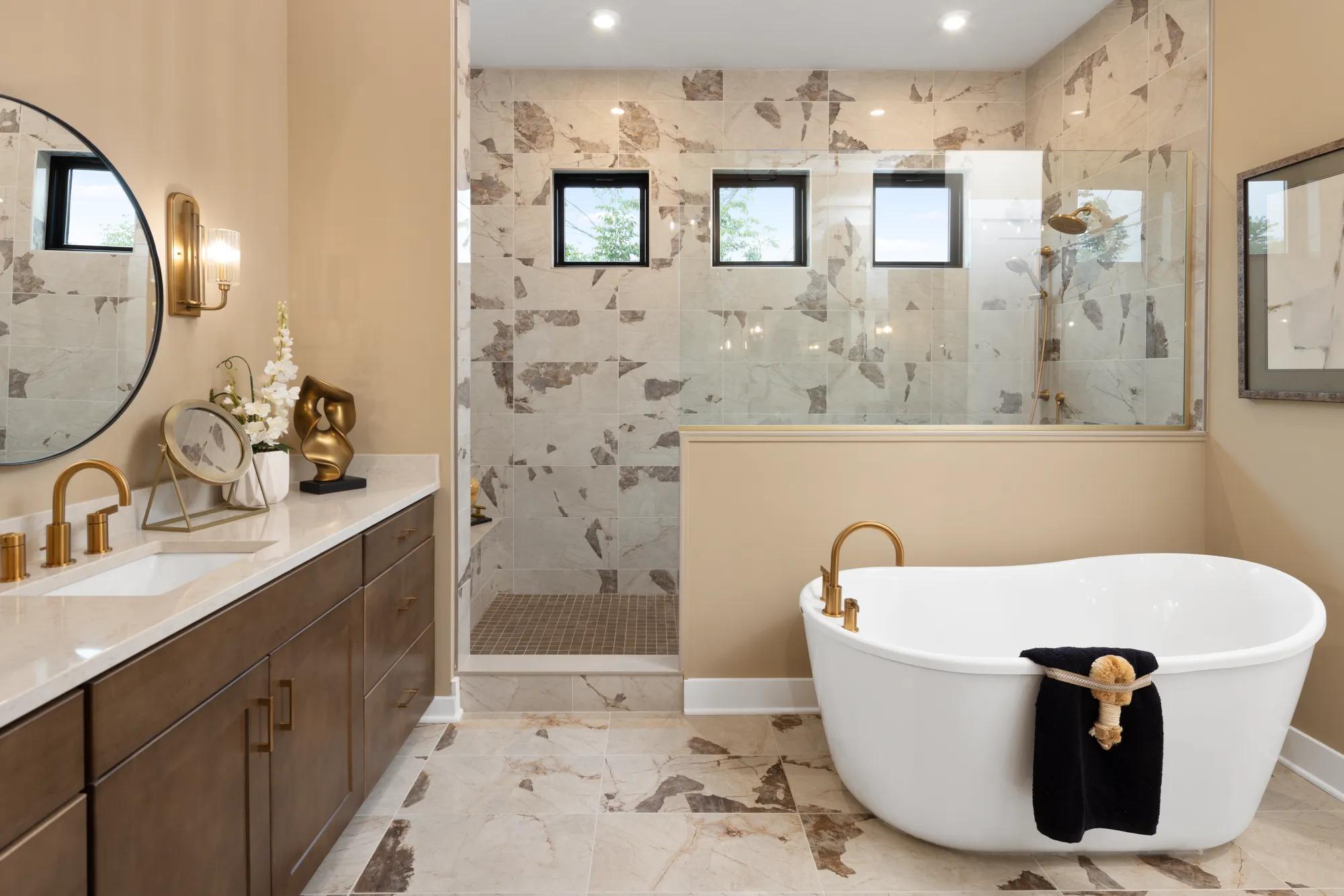 Custom home primary bathroom with tile shower, freestanding tub, and wood vanity 