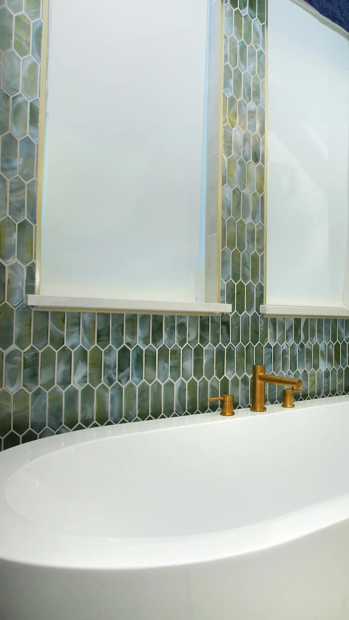Freestanding tub with green tile wall in new home primary bathroom