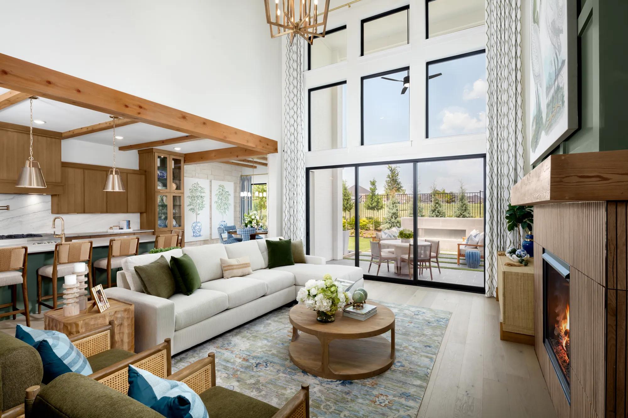 New home open floor plan family room with two-story ceiling, wall of windows, and fireplace