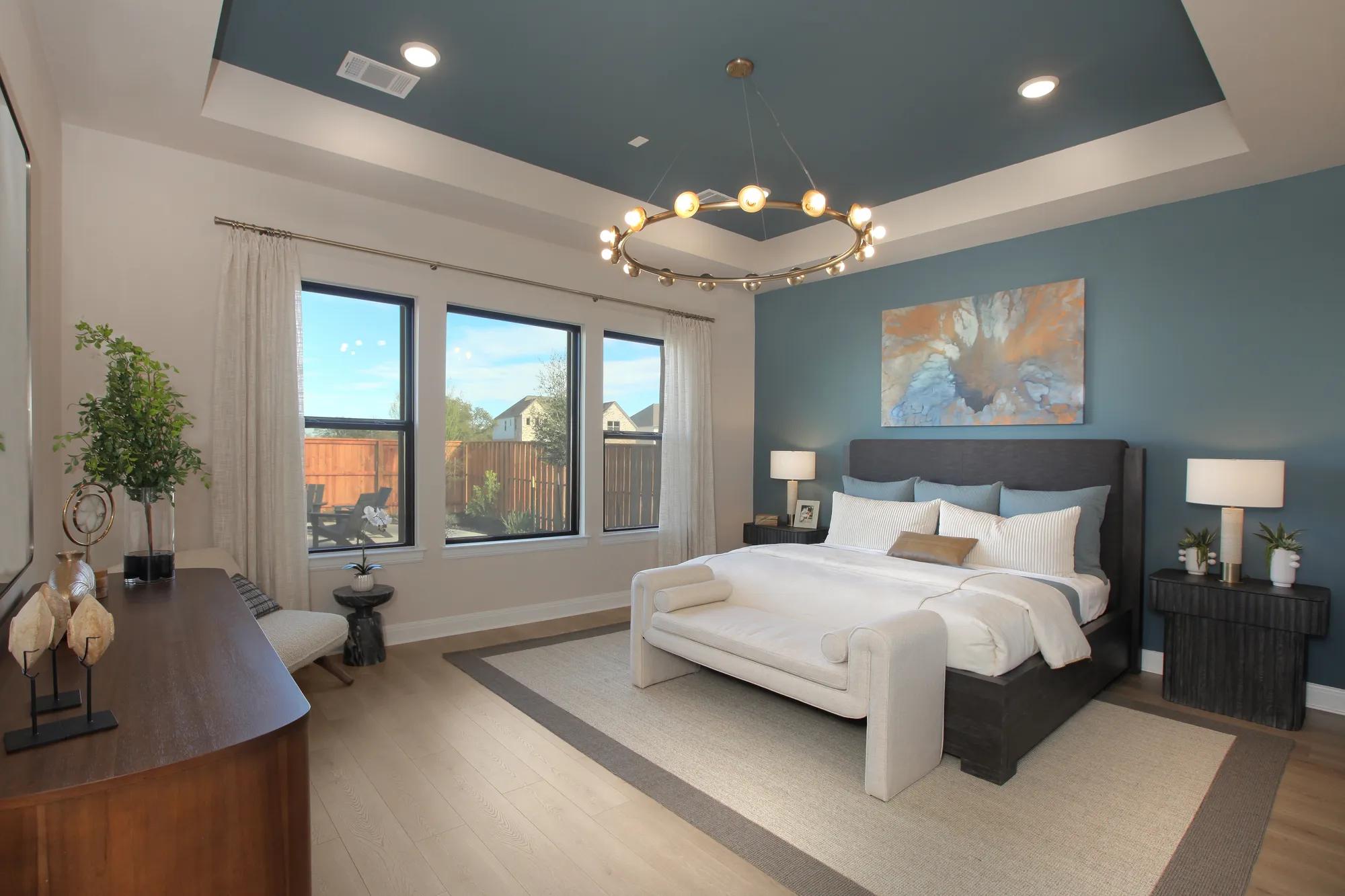Custom home primary bedroom with blue accent wall and blue painted ceiling