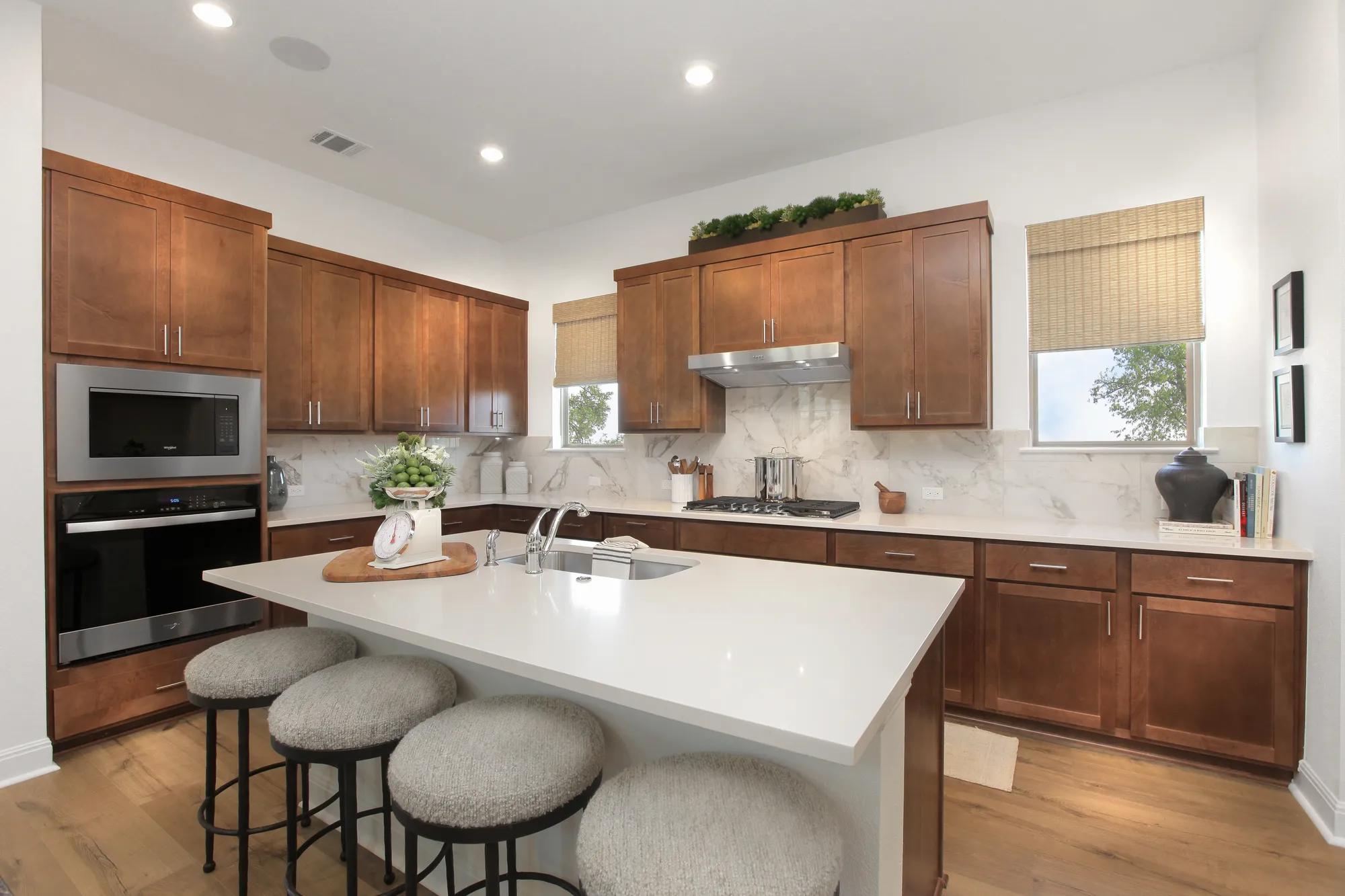 Custom home kitchen with windows, dark wood cabinets, light marbled backsplash, and stainless steel finishes