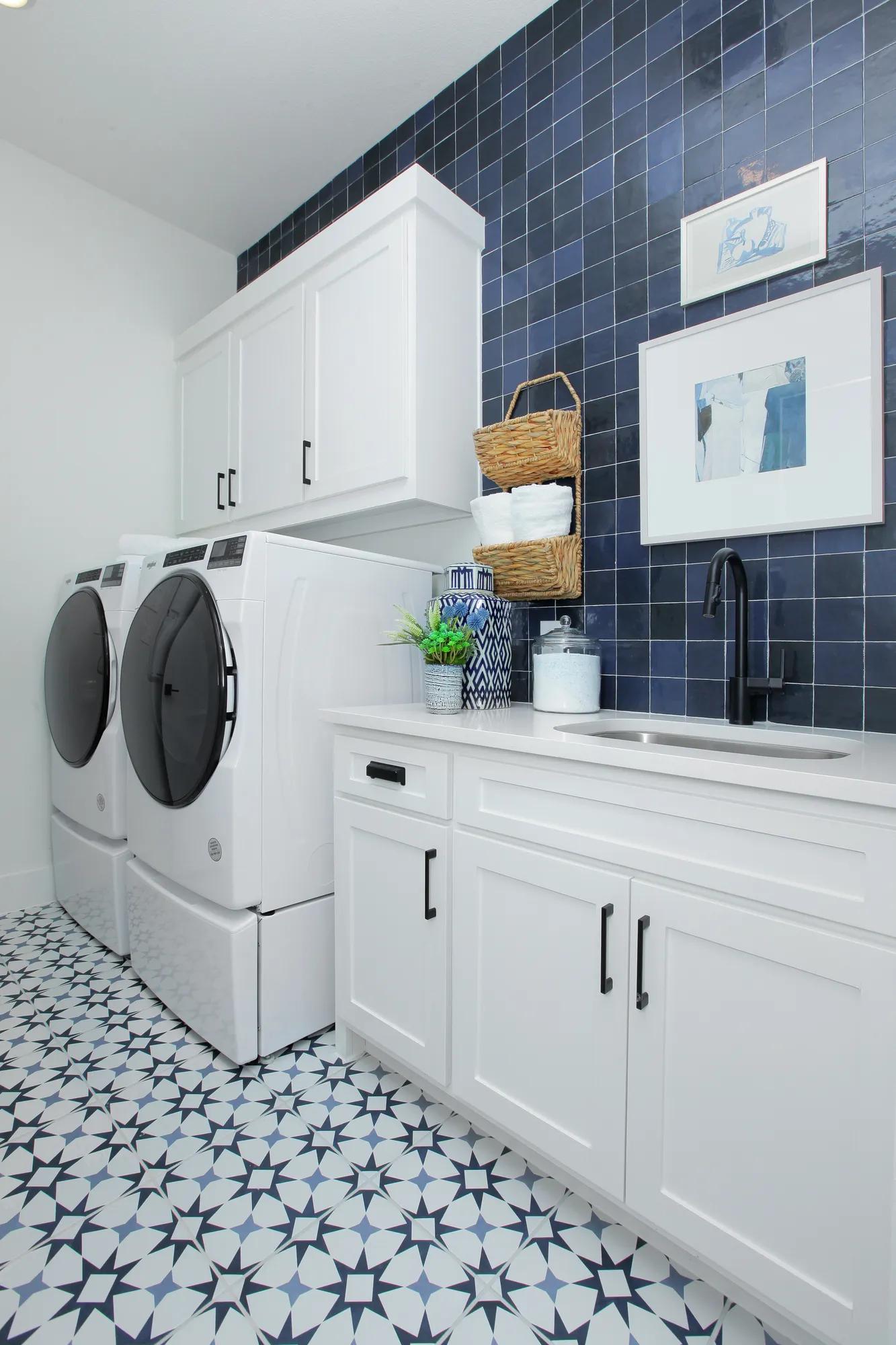 New home laundry room with white cabinets and blue tile wall