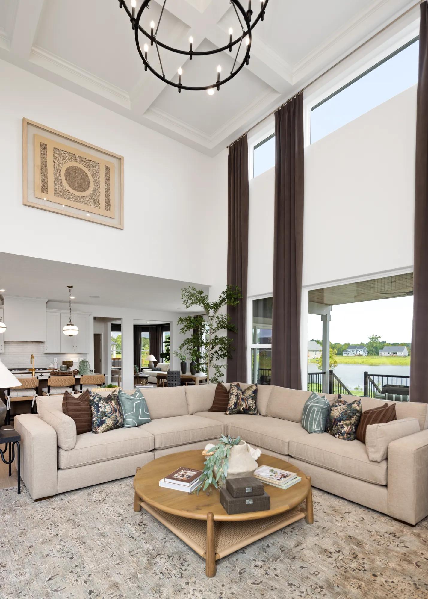 Custom home family room with two-story ceiling, coffered ceiling accent, and modern industrial chandelier 