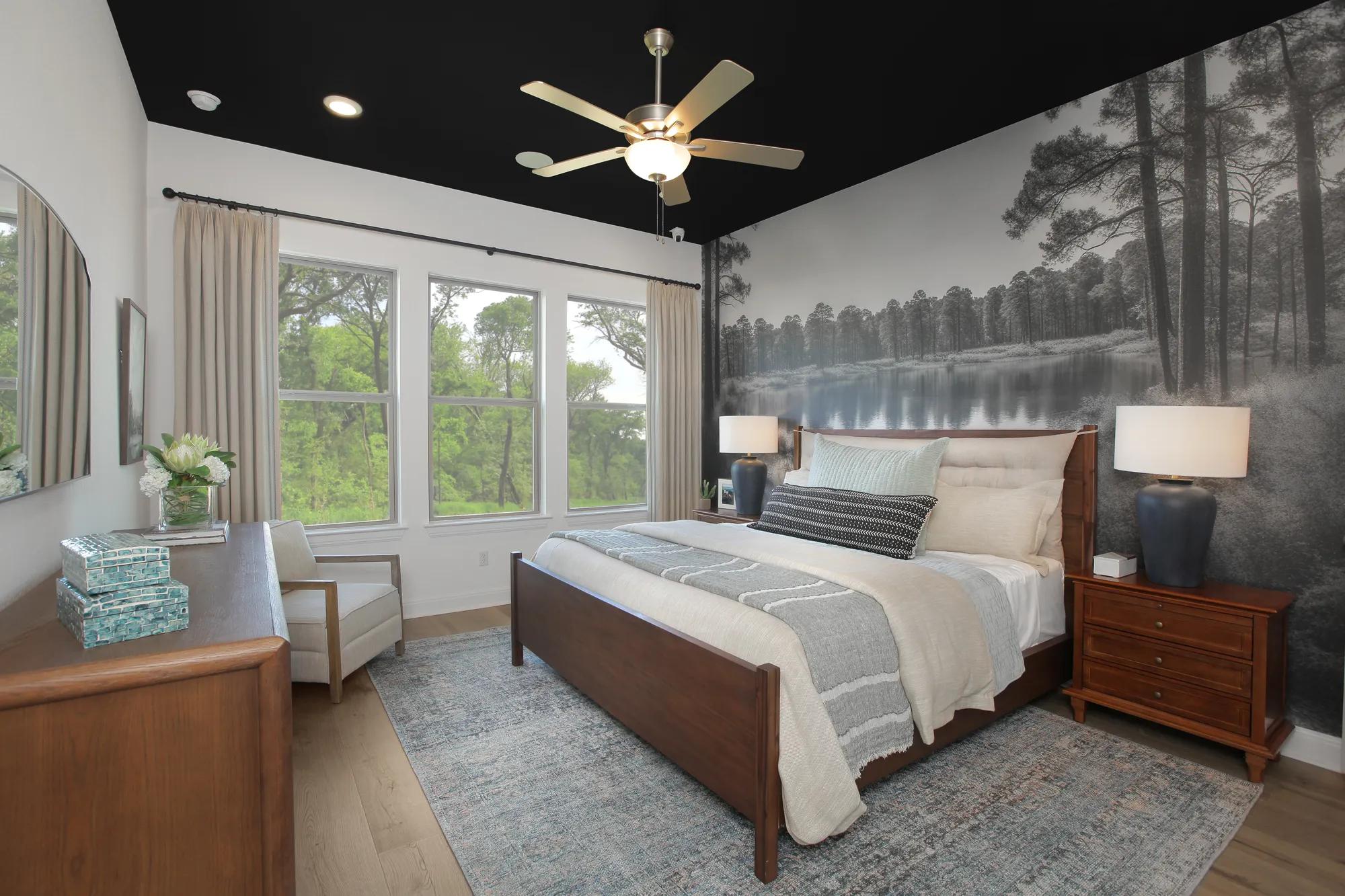 Custom home primary bedroom with black painted ceiling and black and white nature scene wallpaper accent wall