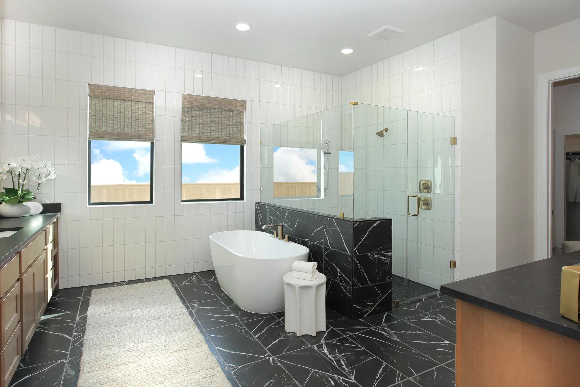 Custom home primary bathroom with white tile wall and marbled black tile floor