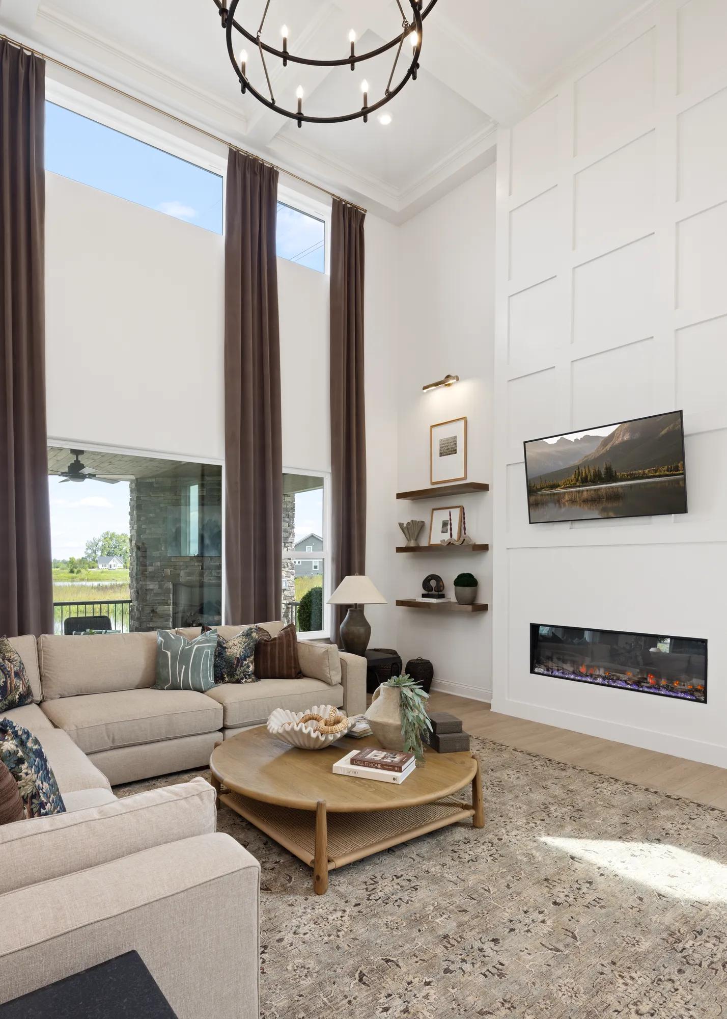 Custom home family room with modern fireplace, two-story ceilings, and wall of windows