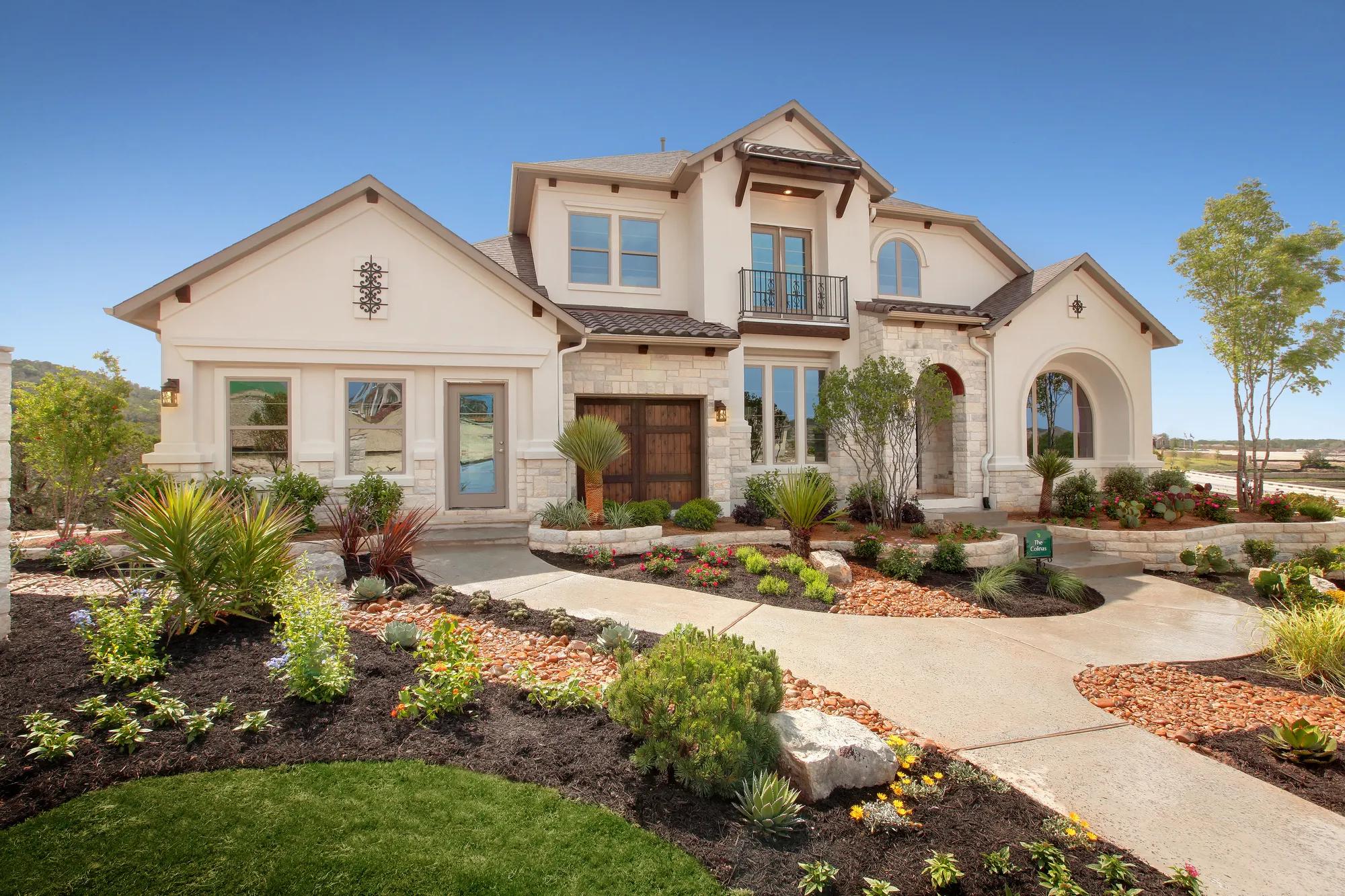 Exterior of a stately two-story home featuring stone detail and exceptional landscaping
