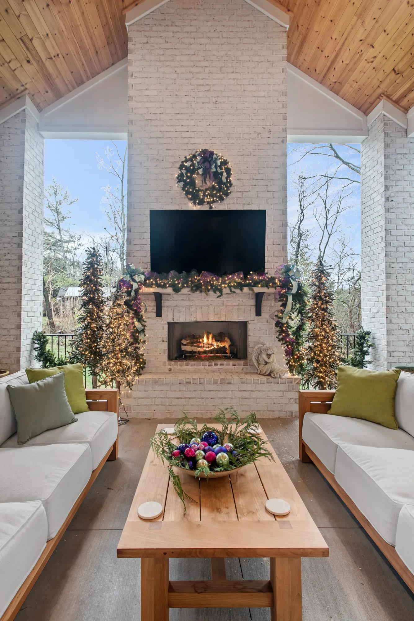 new home outdoor living area fireplace with holiday garland, wreath and small Christmas trees