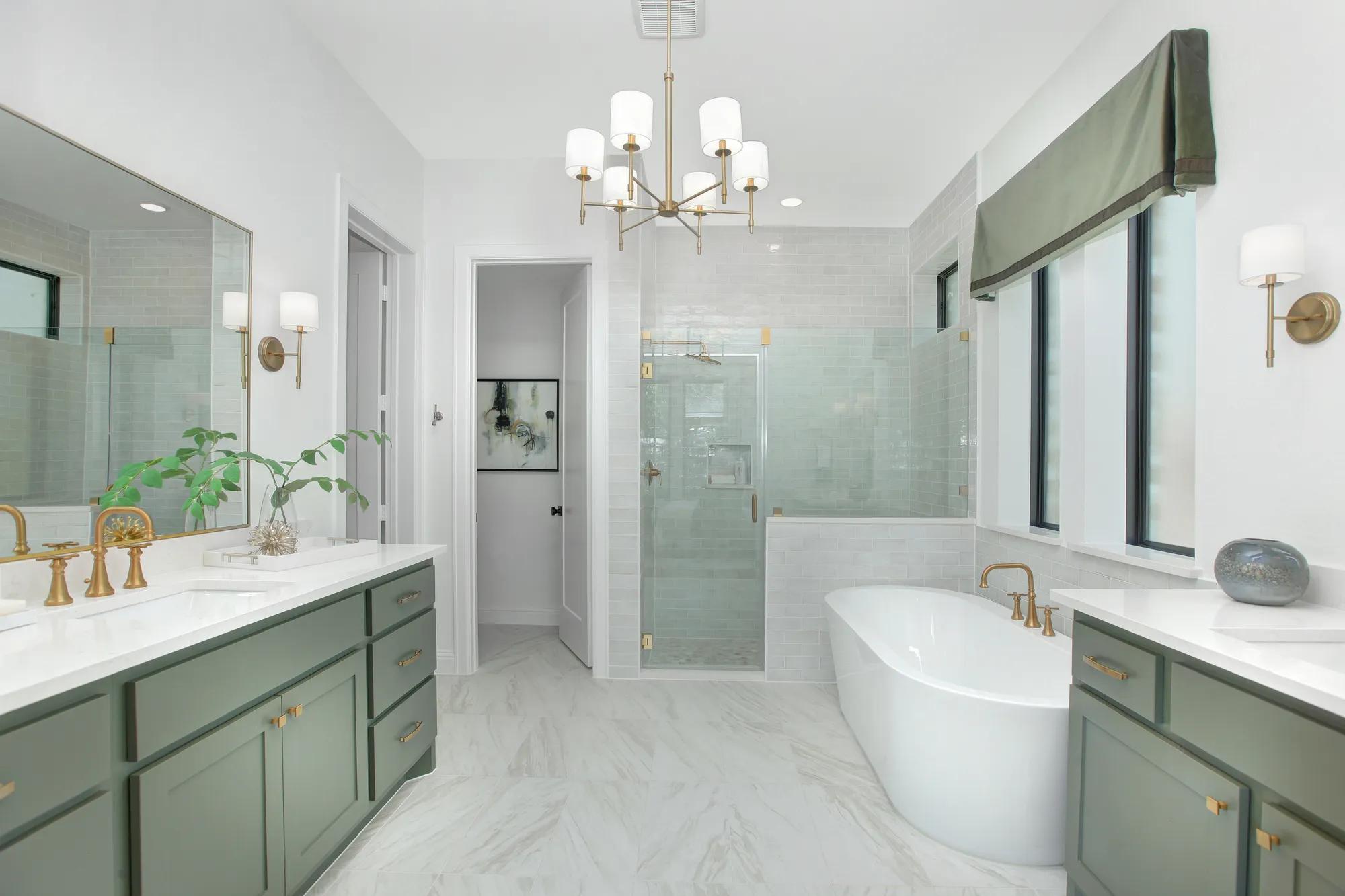 Custom home primary bathroom with glass shower, freestanding tub, and green double vanities