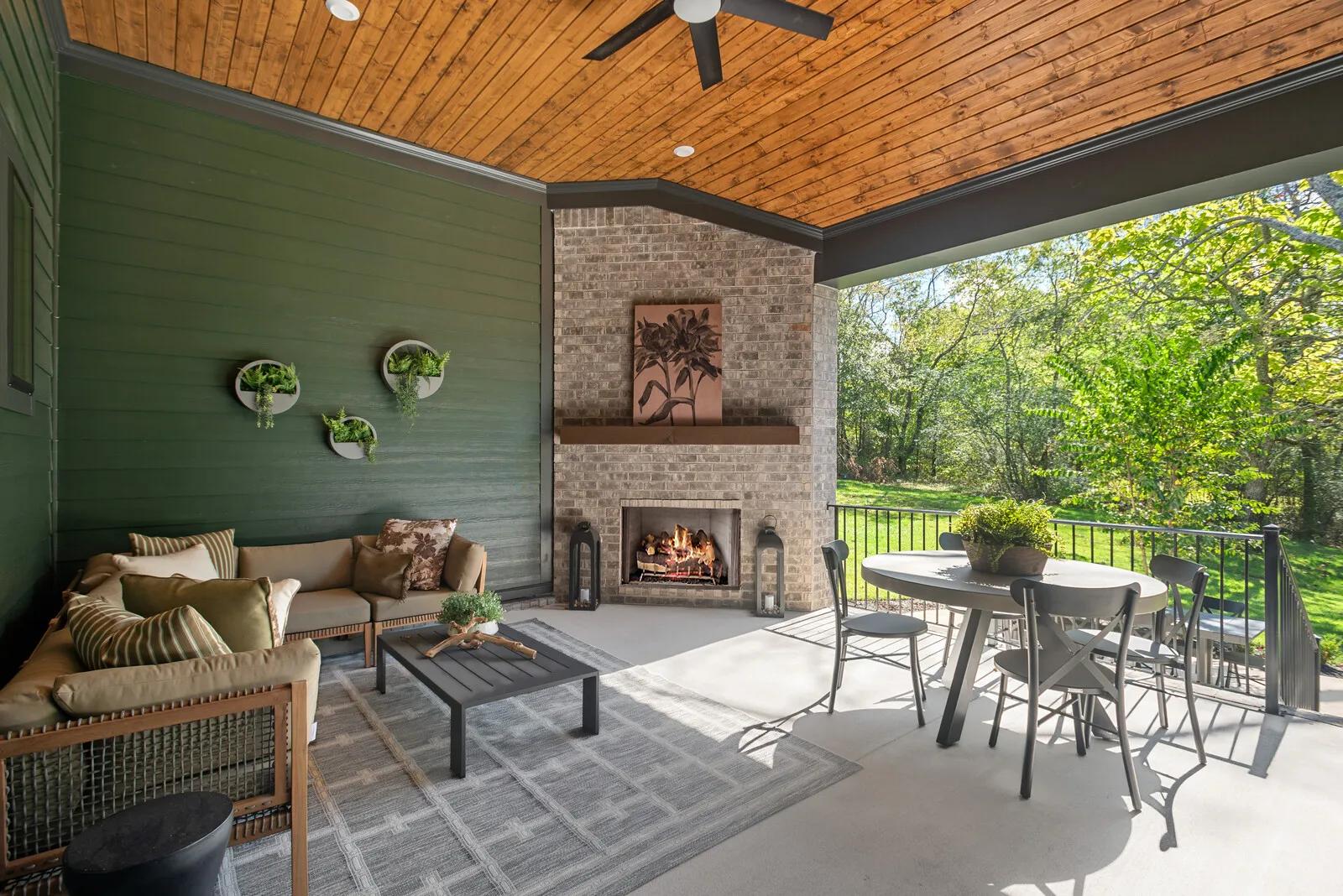 Custom home outdoor living area with wood panel ceiling and brick fireplace