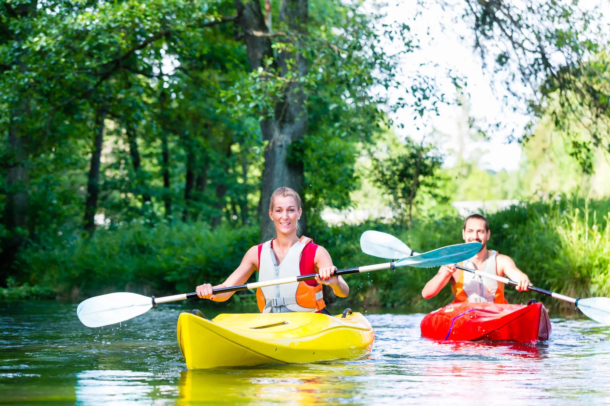 Two friends paddling with canoe on forest river