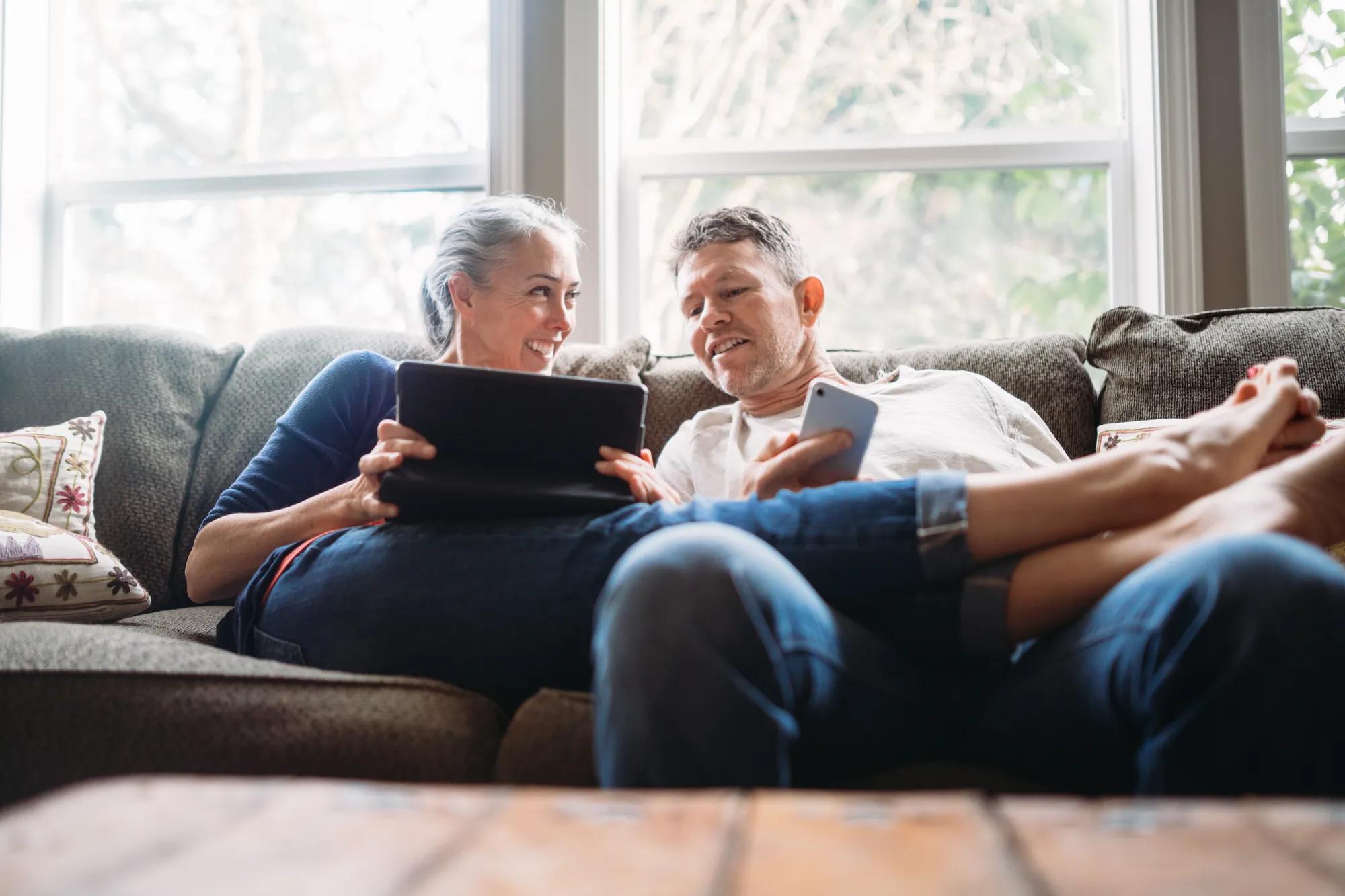 Couple using phone and tablet in home
