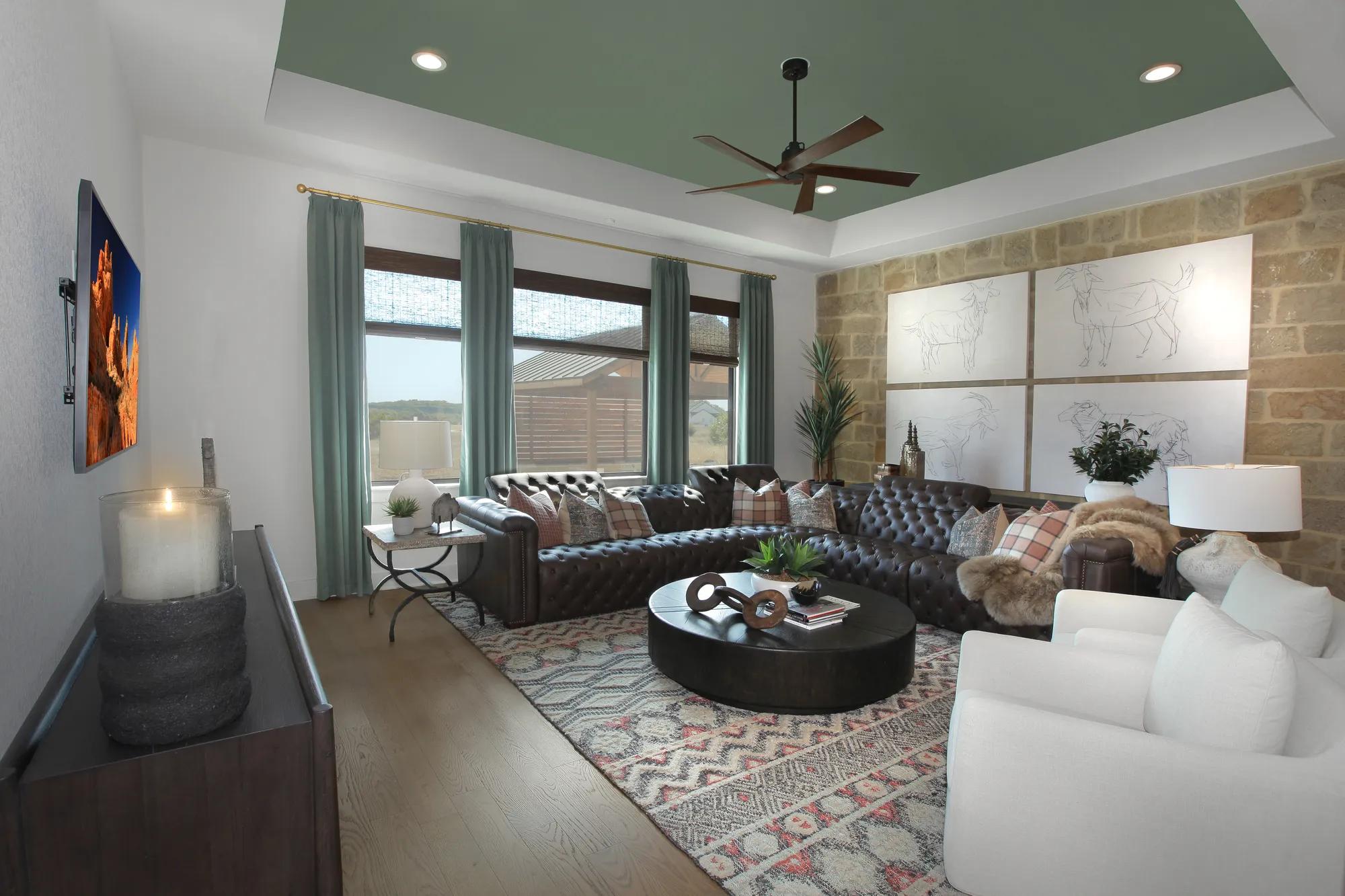 Gameroom with multiple seating zones, ceiling fan, and entertainment-ready layout in a Drees home