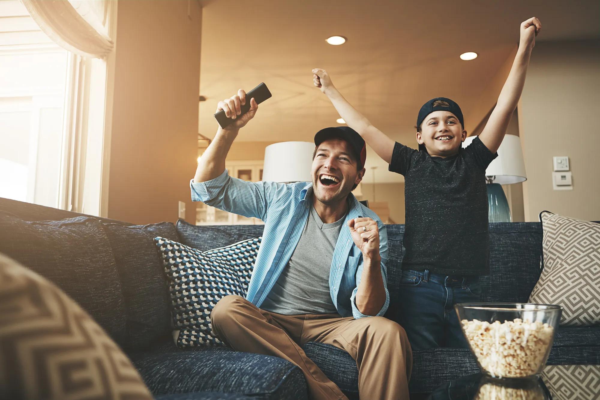 Happy father and son watching tv in home
