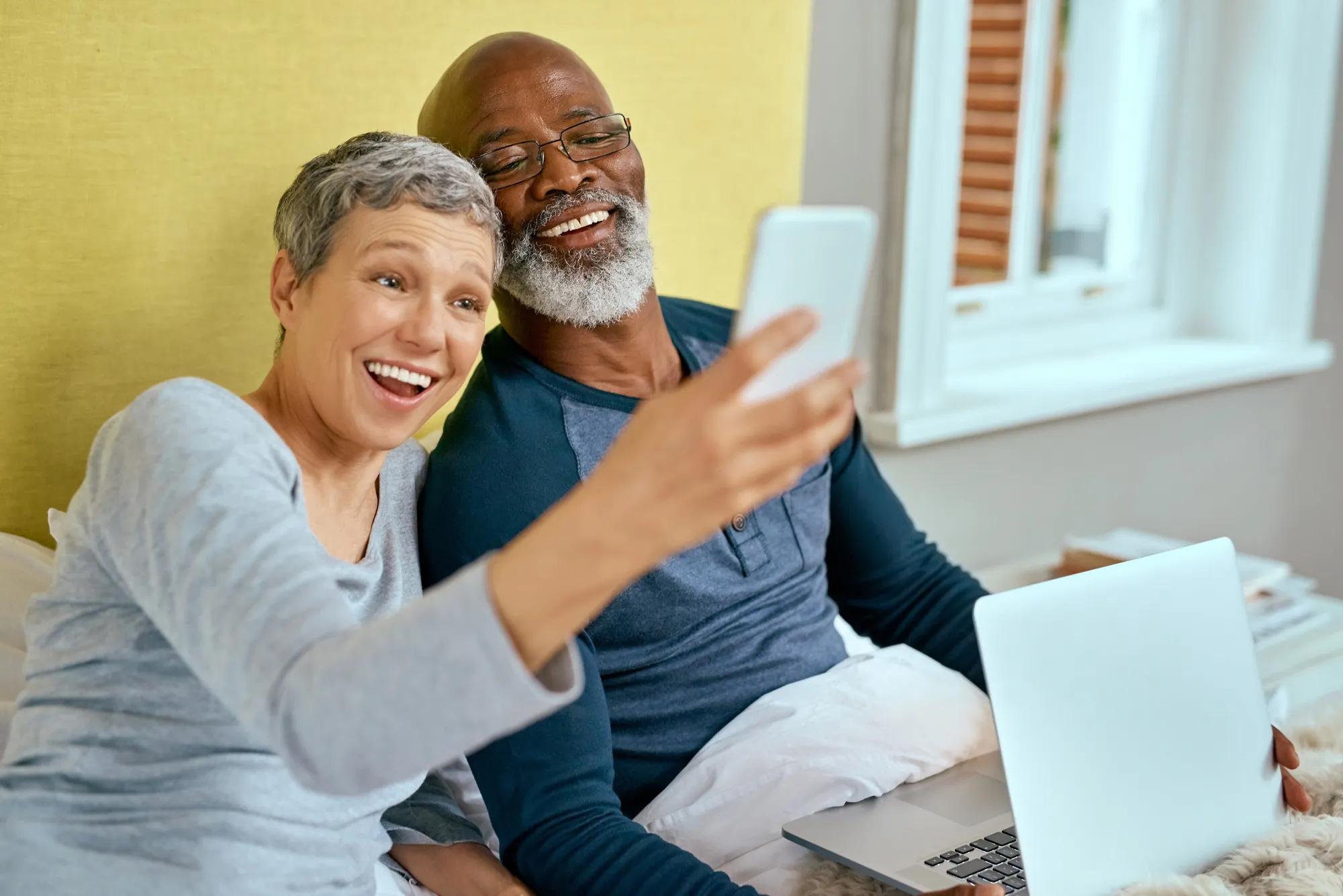 Couple using phone and laptop at home