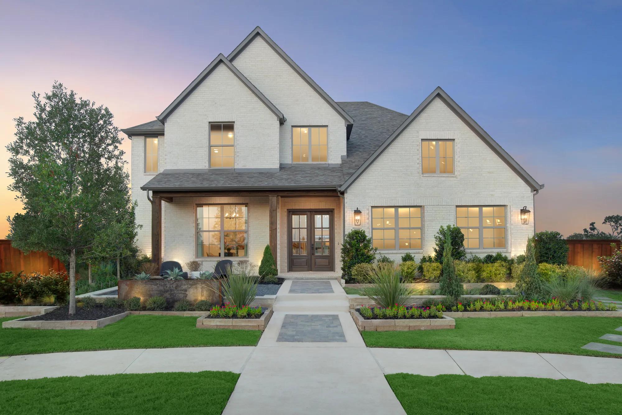 Light brick custom home exterior with dark wooden doors and columns