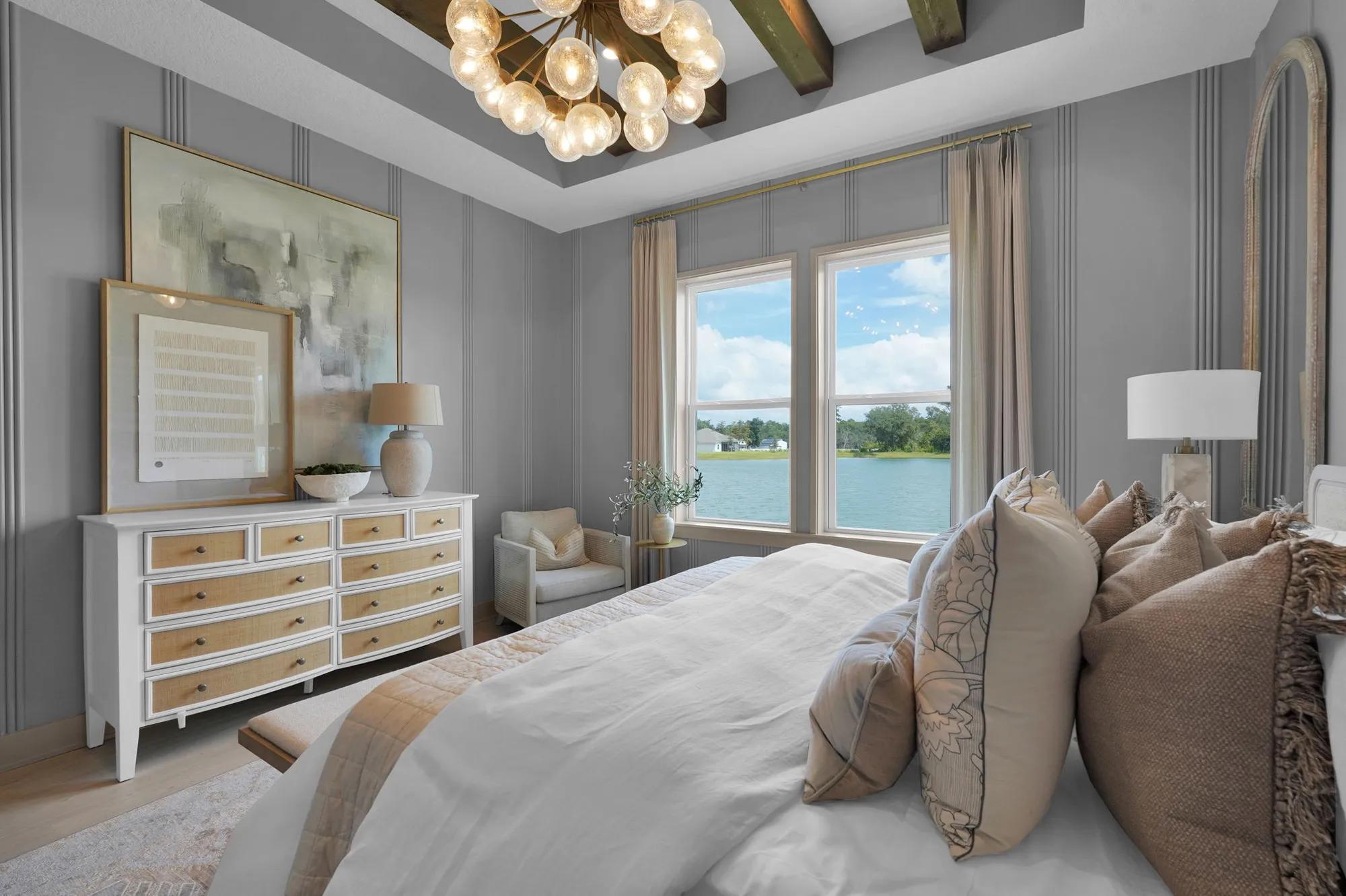 Custom home primary suite bedroom with wood beam ceiling and orb chandelier 