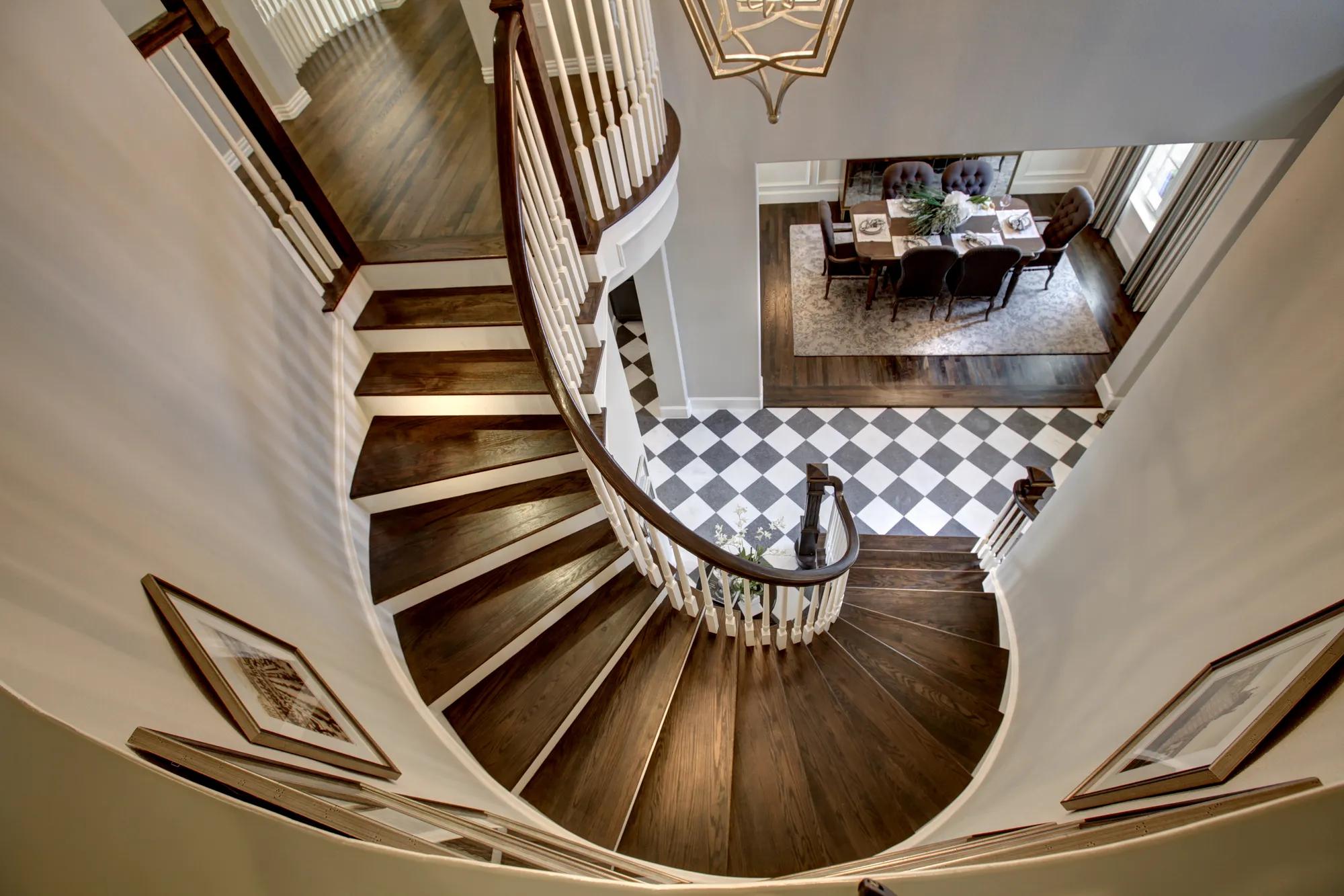 black and white checkerboard tile floor two story foyer with white railing spiral hardwood staircase with pendant light