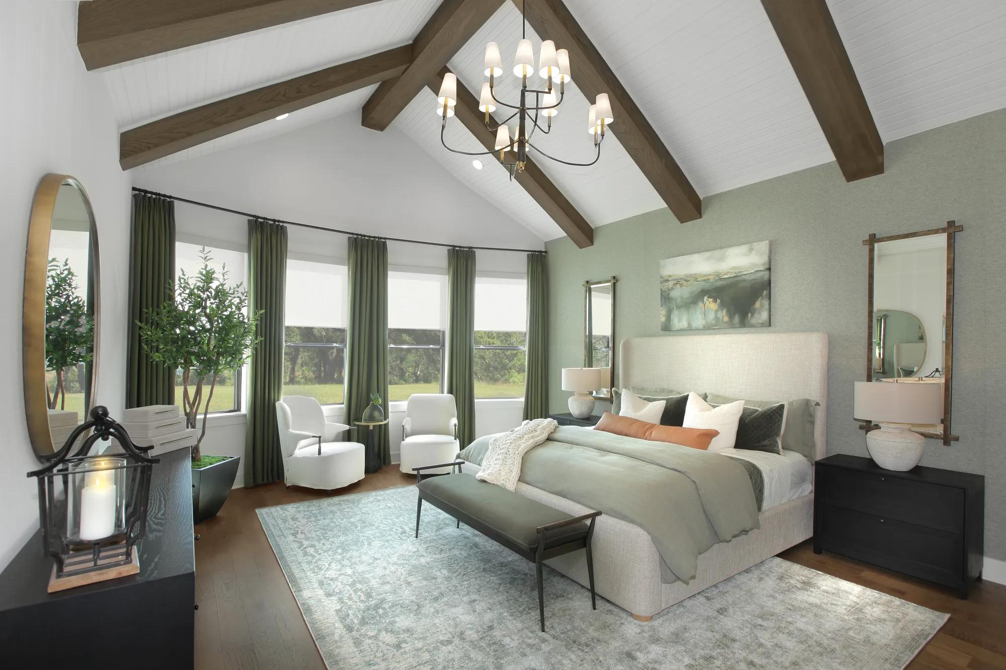 Primary suite with vaulted ceiling, wood beams, seating area, and natural light in a Drees custom home