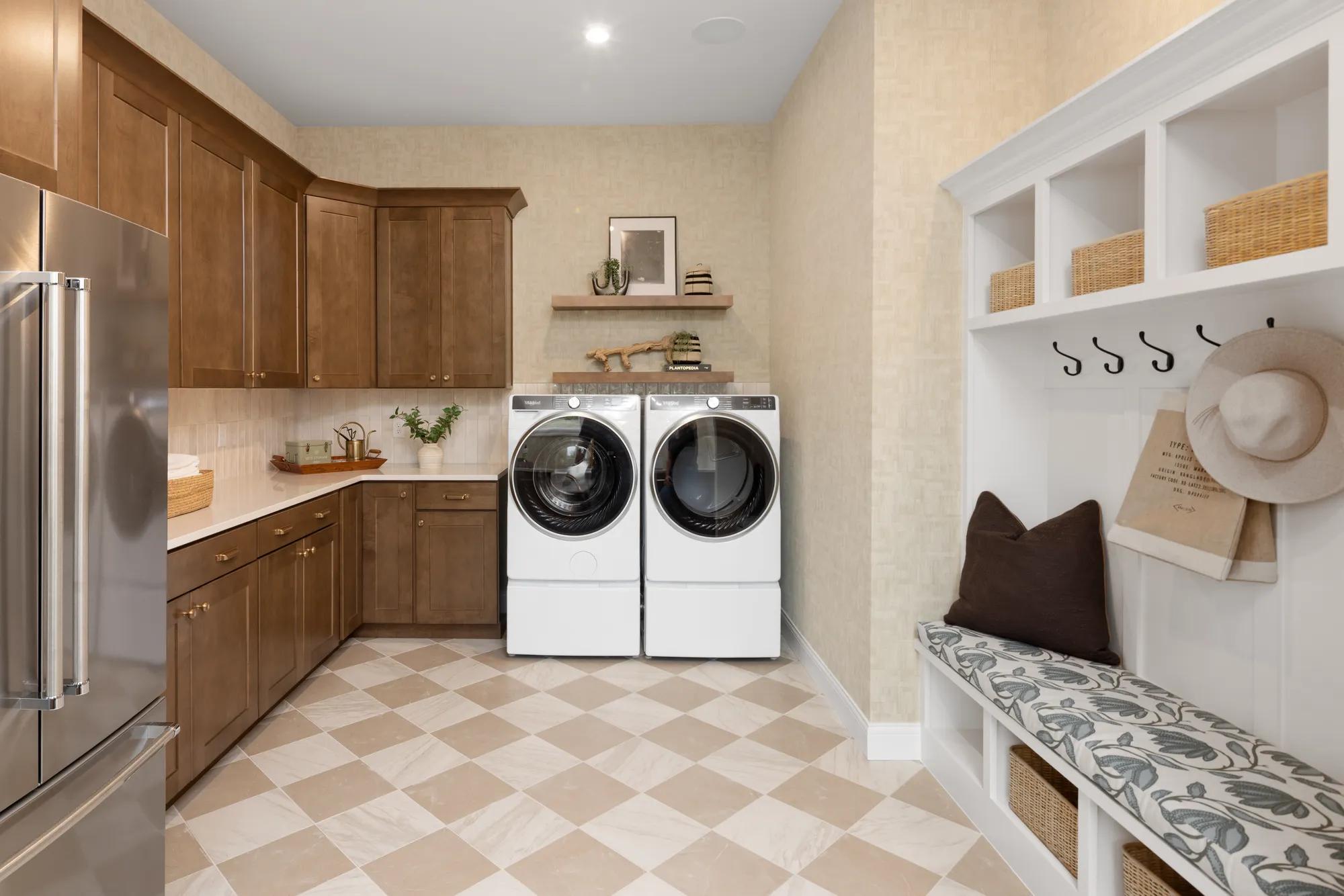 New home laundry room and mudroom with built in bench, wood cabinets, and extra refrigerator 