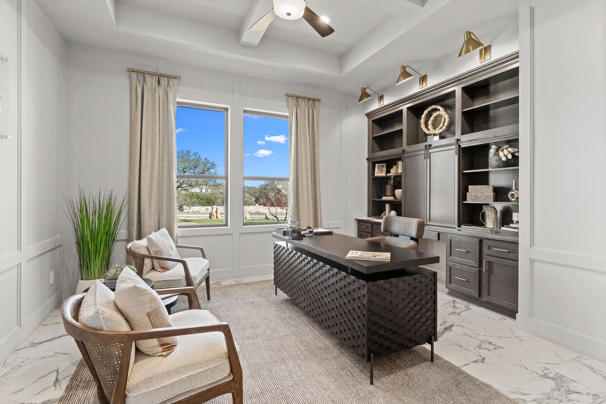 Luxury home office with marble tile floor, wainscoting, built-in wooden cabinets, and coffered ceilings