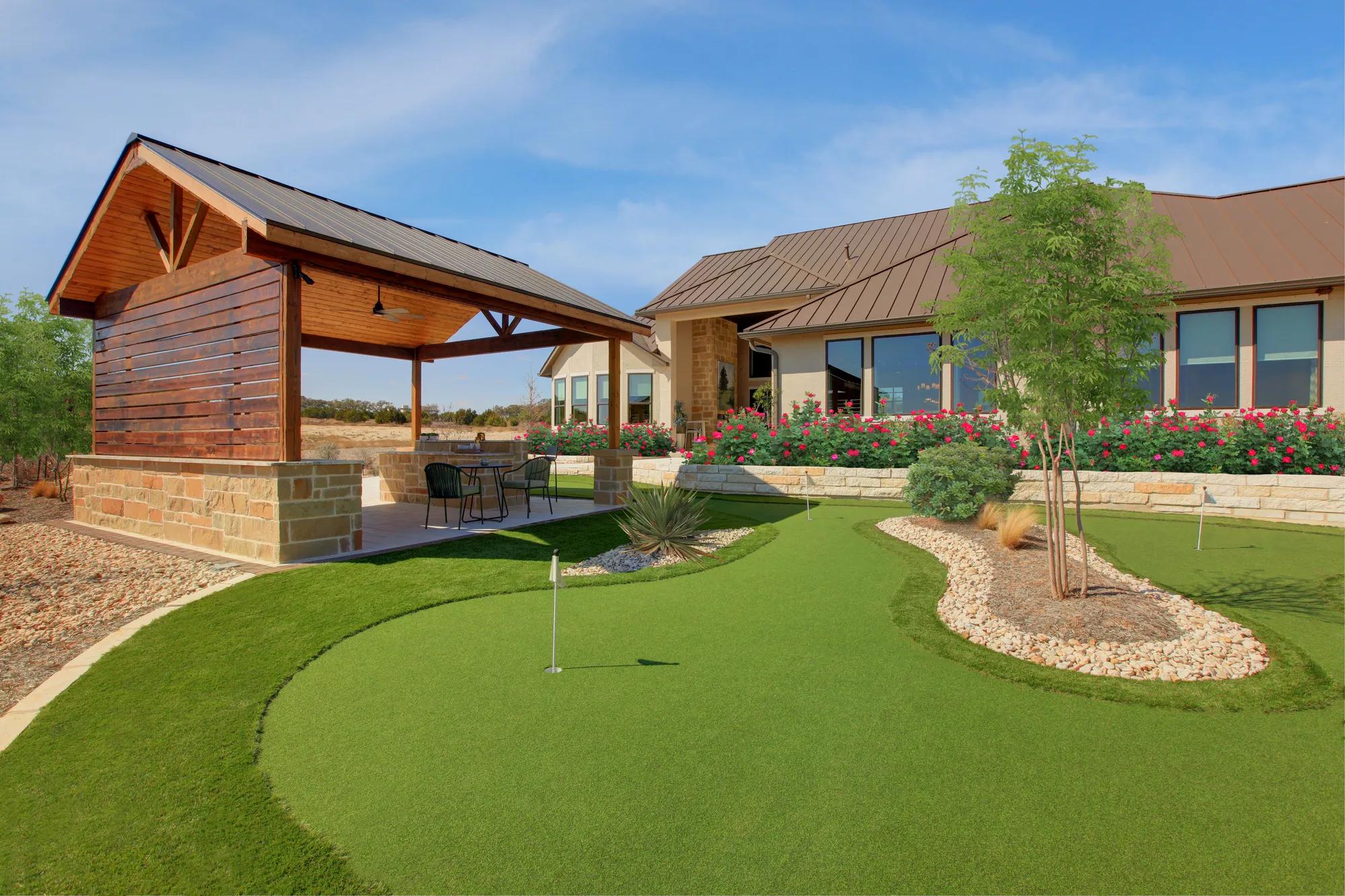 Backyard outdoor living with covered patio and putting green