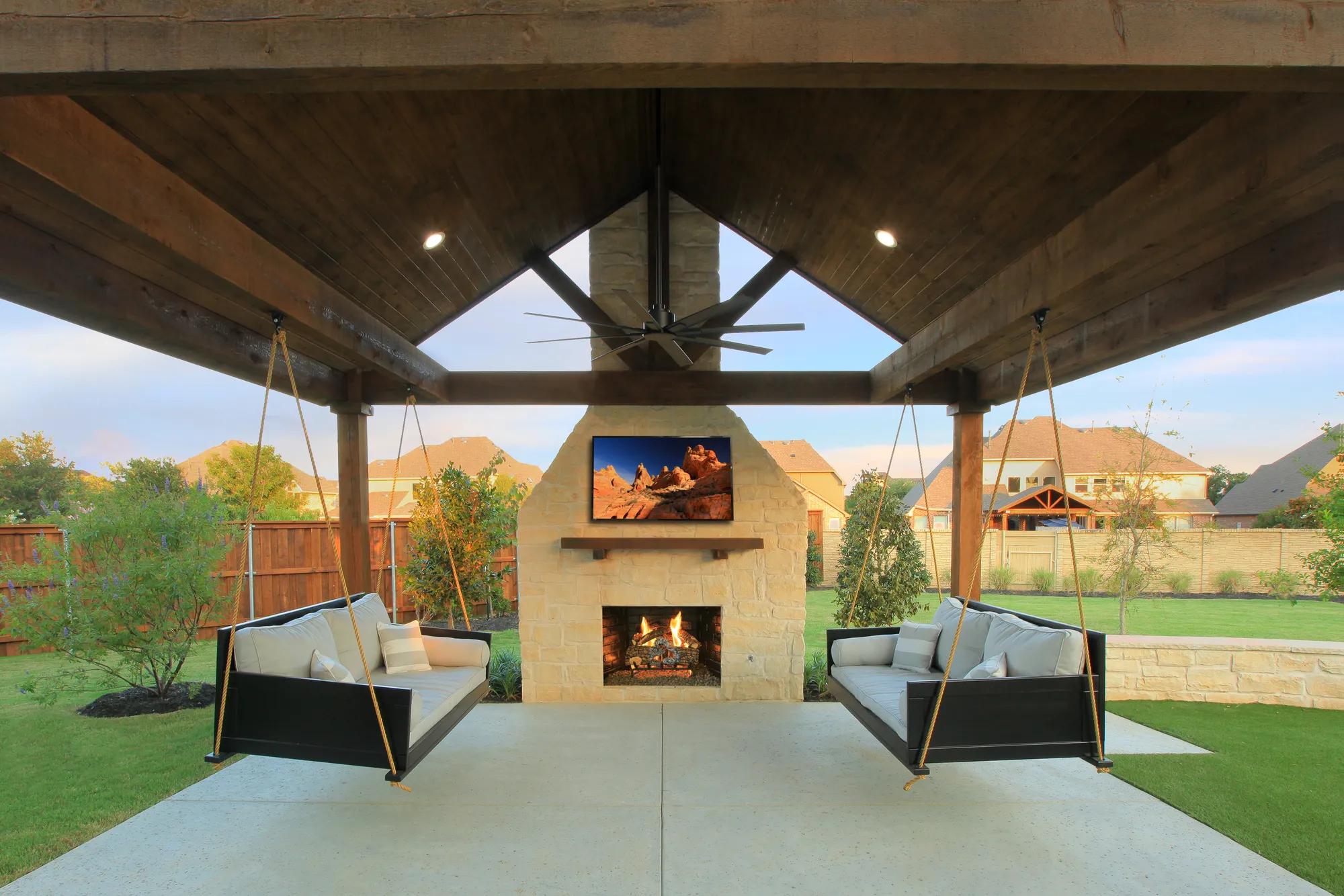 custom outdoor living area with fireplace and swings