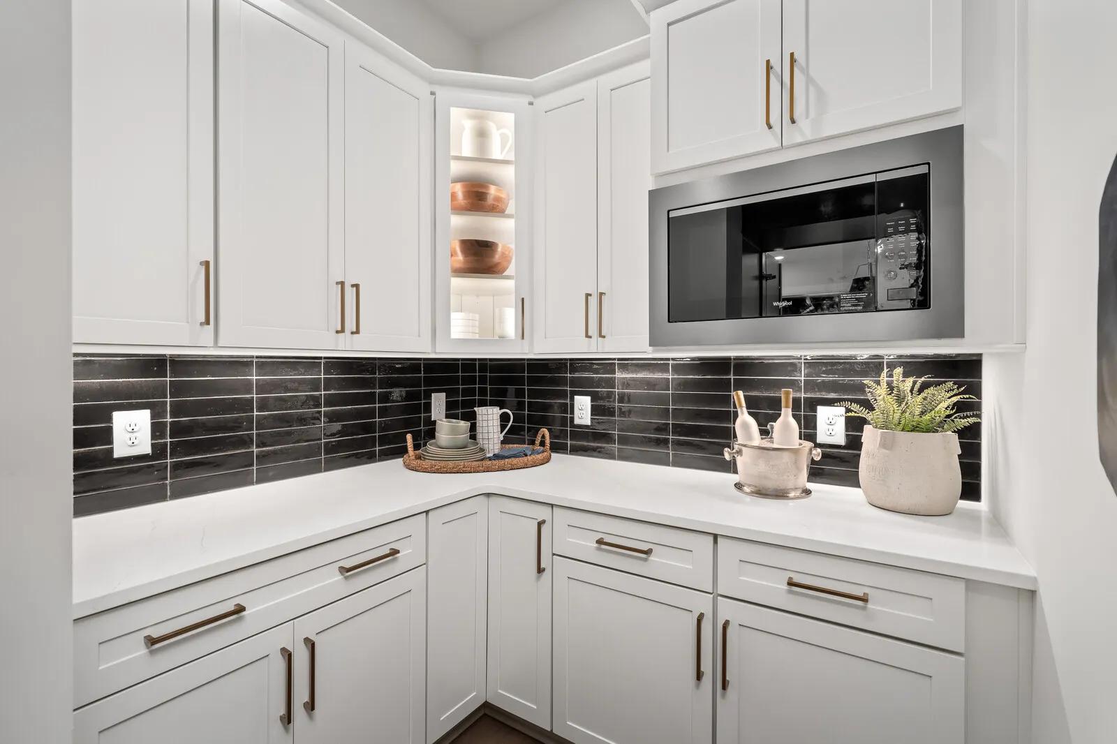 Custom home working pantry with black backsplash and white cabinets