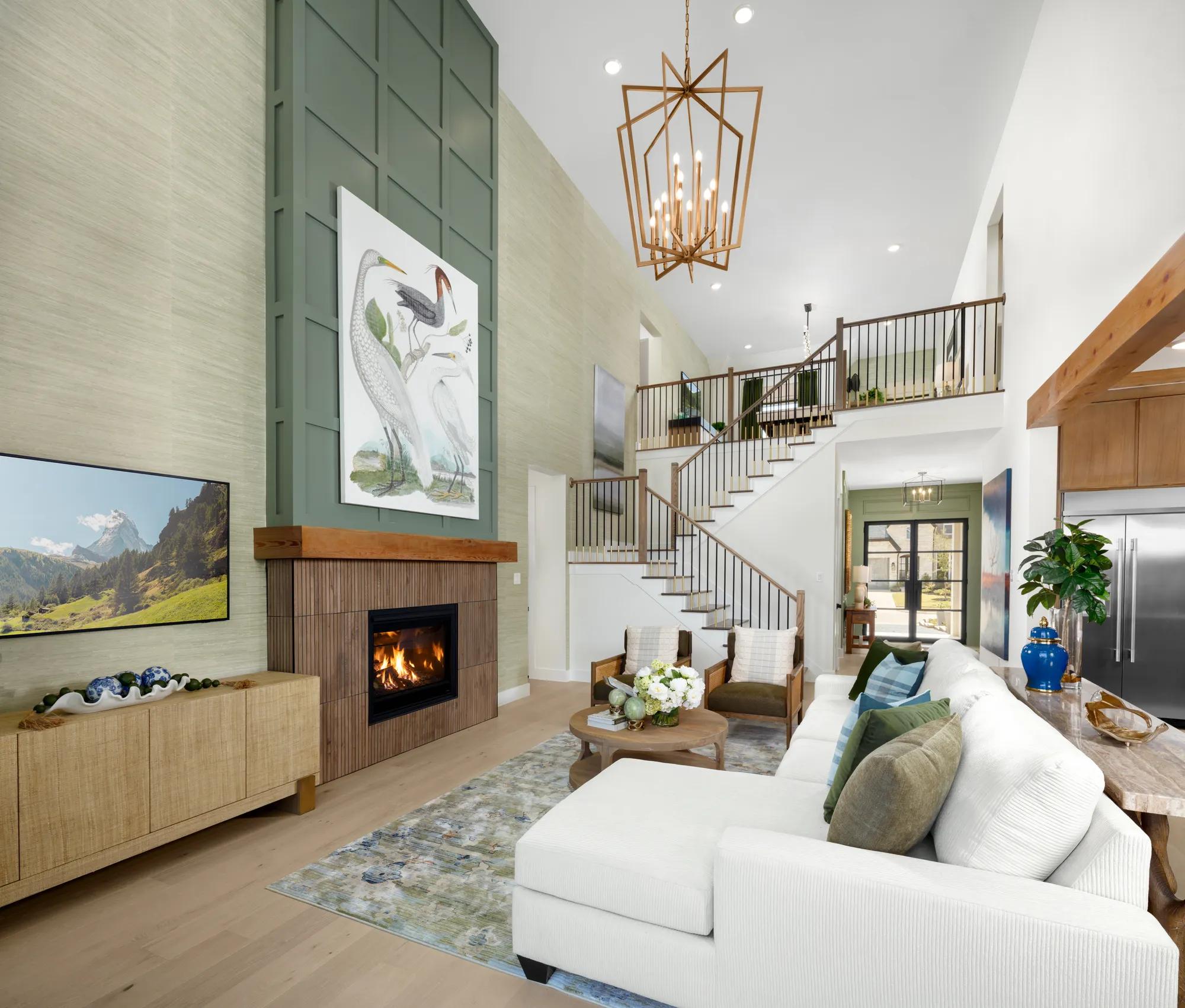 New home two-story family room with green walls, dark wood fireplace, and open staircase to upstairs gameroom